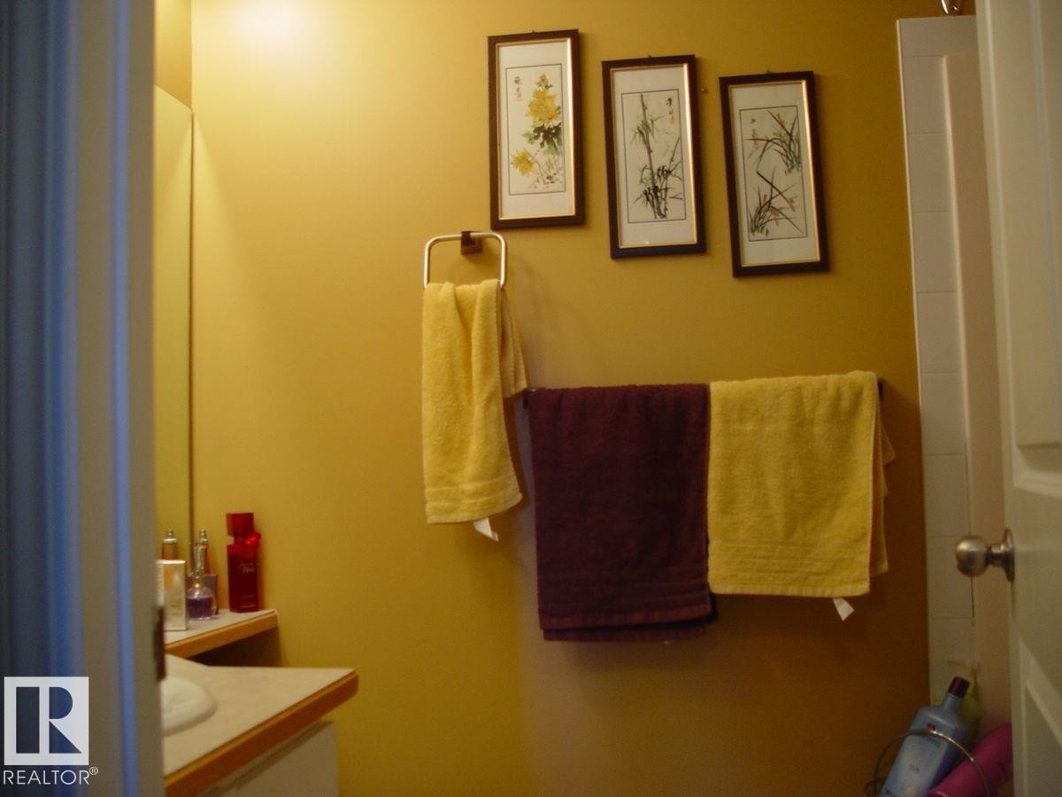 Bathroom featuring a wall-mounted towel rack and vanity with a light-colored countertop - #116 10535 122 St Nw, Edmonton, AB - Indoor Photo Showing Other Room