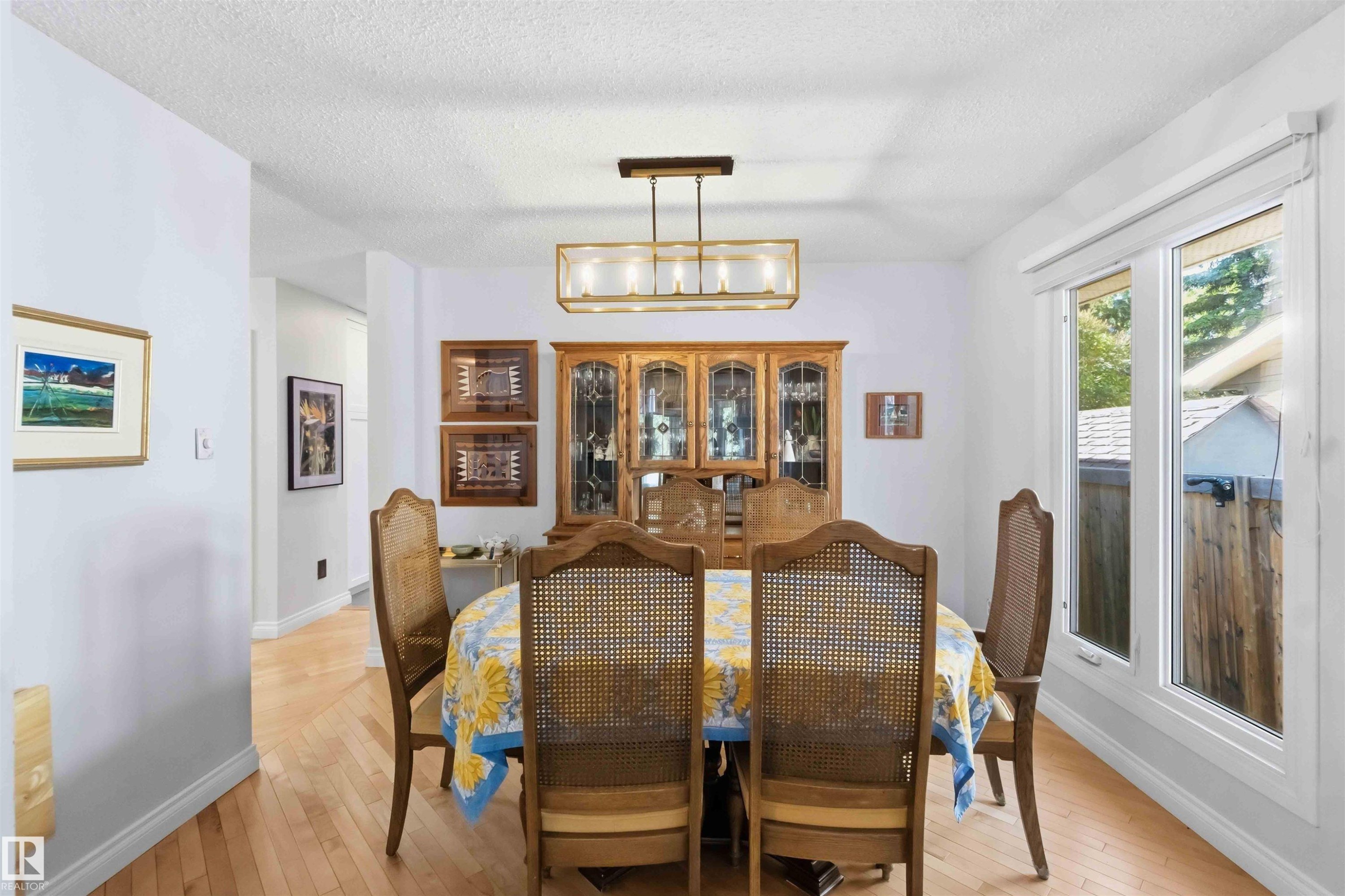 Bright dining area featuring hardwood flooring, a modern linear chandelier, and expansive windows - 31 Gariepy Crescent, Edmonton, AB