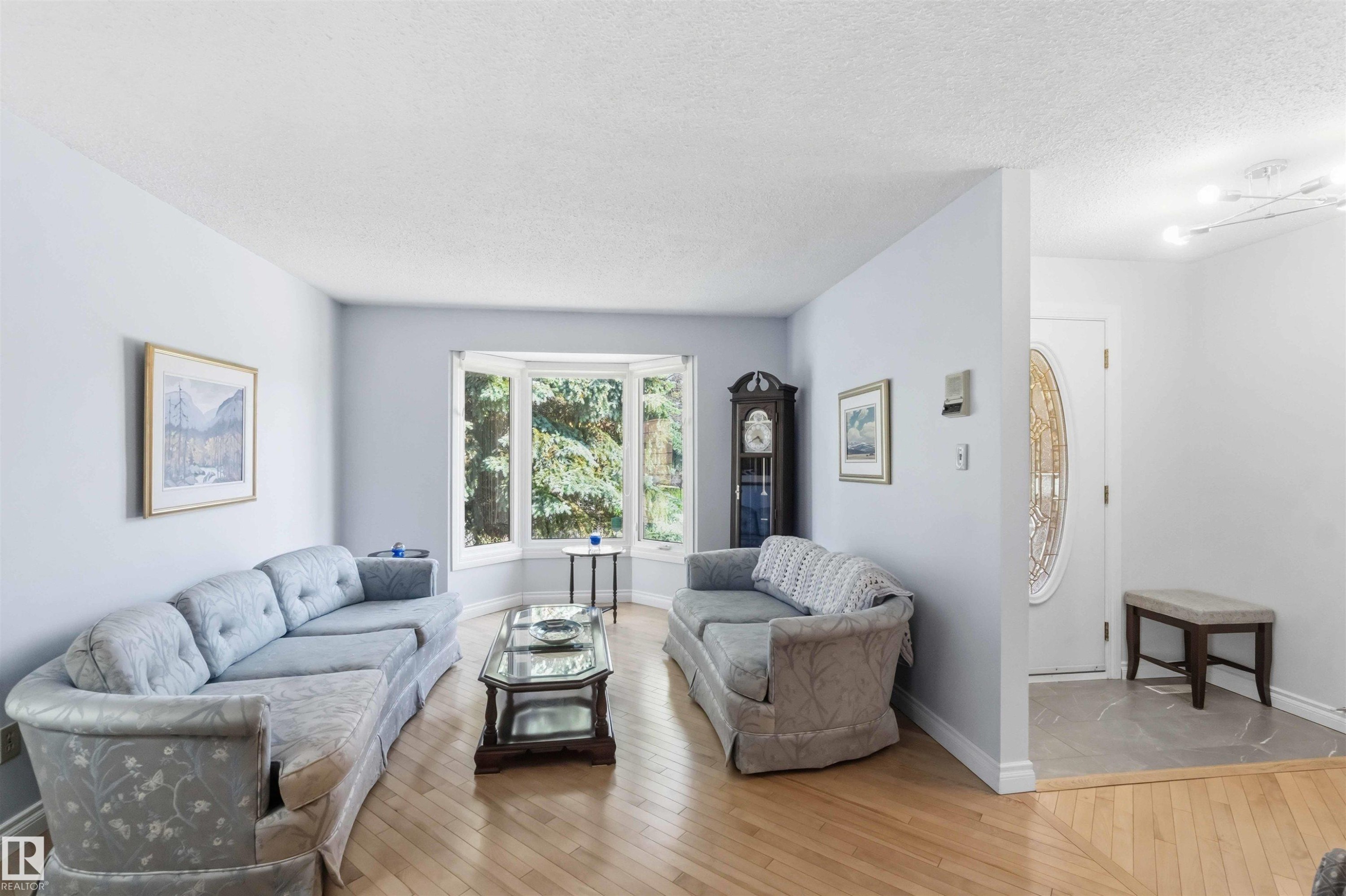 Living area featuring light wood-finish flooring and a prominent bay window - 31 Gariepy Crescent, Edmonton, AB