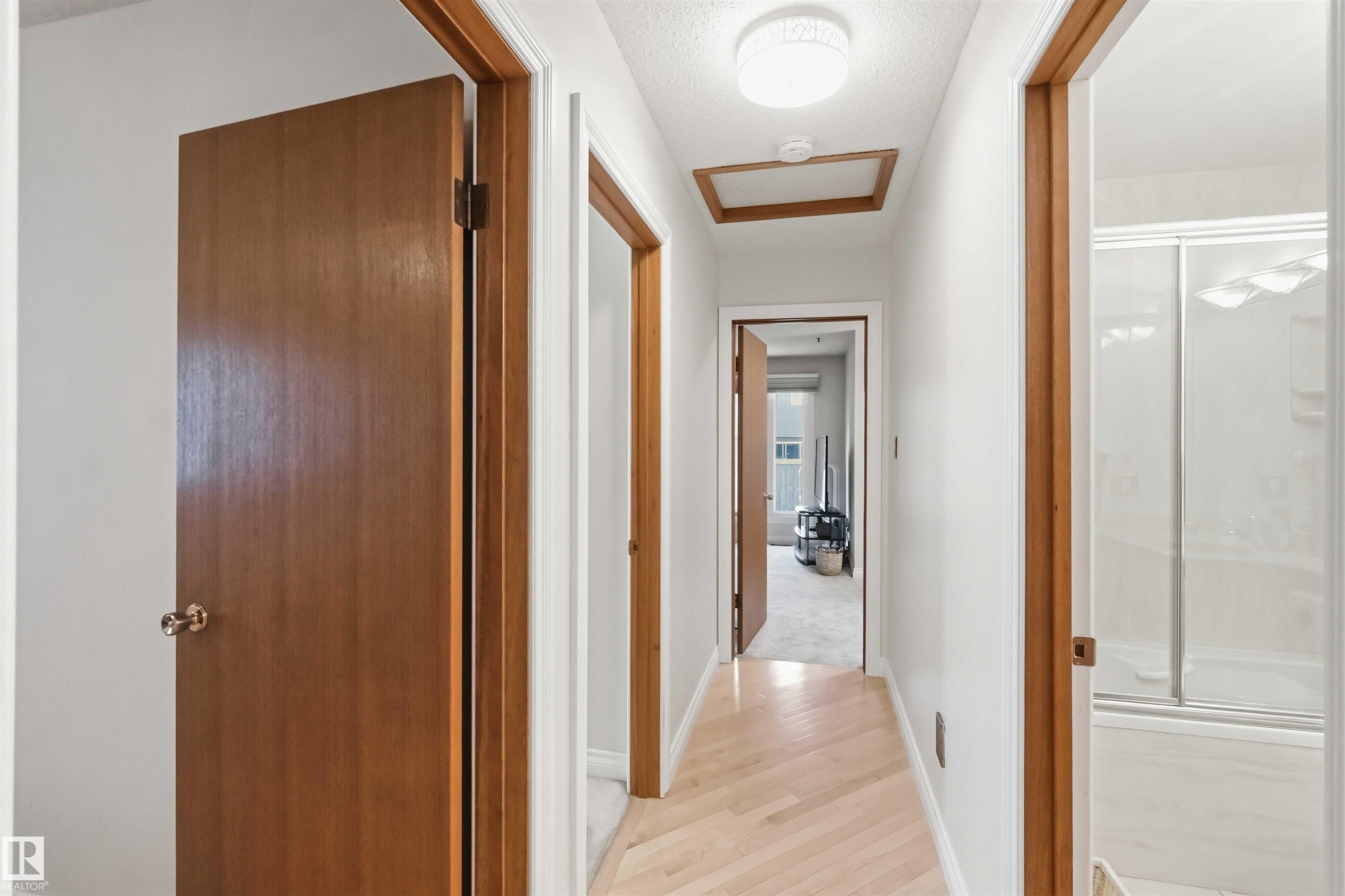 Bright hallway featuring light wood-finish flooring, white walls, and wood-trim doorways - 31 Gariepy Crescent, Edmonton, AB