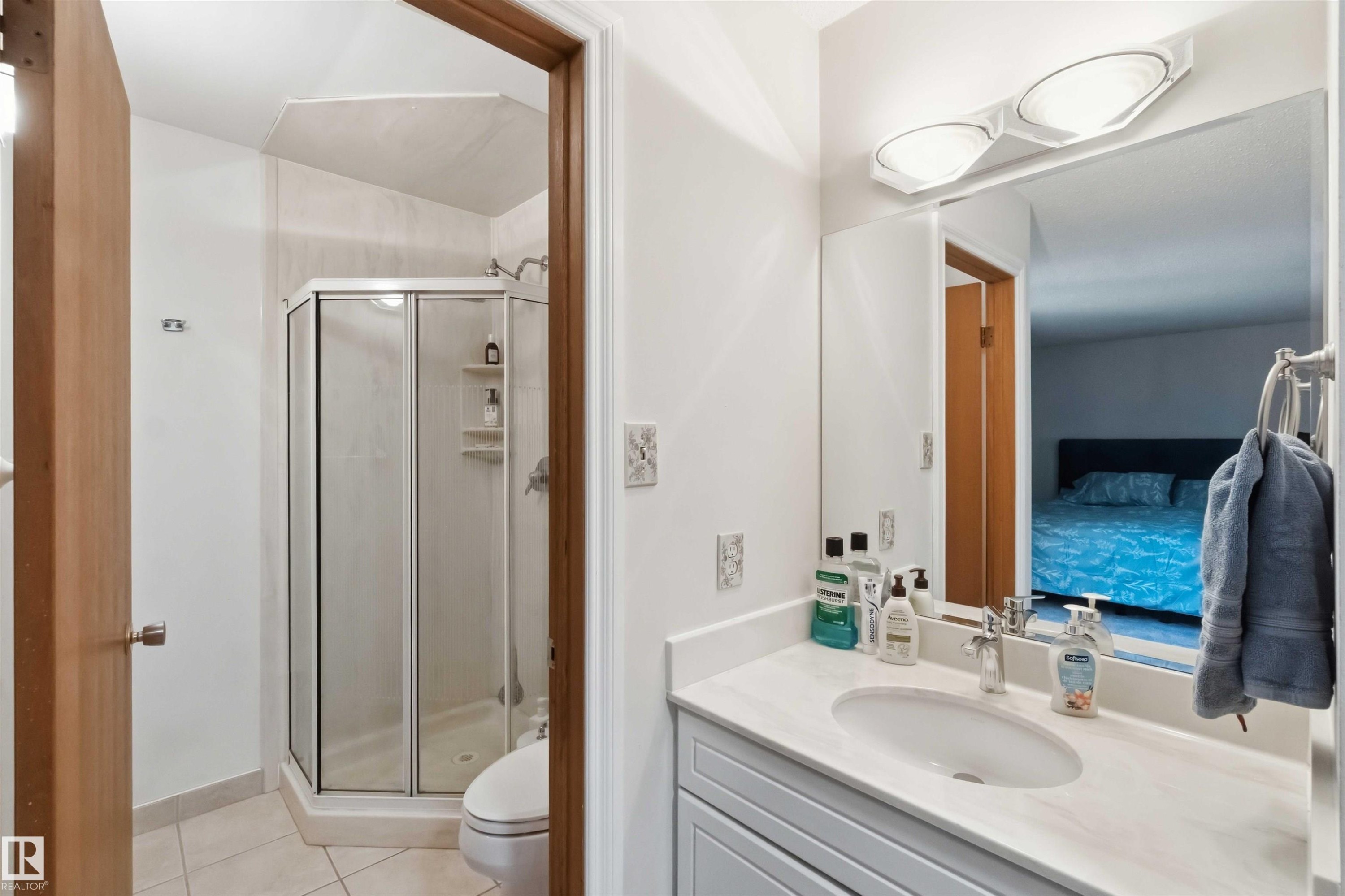 Bathroom featuring a shower enclosure with a glass door, a toilet, and a vanity with a white countertop - 31 Gariepy Crescent, Edmonton, AB