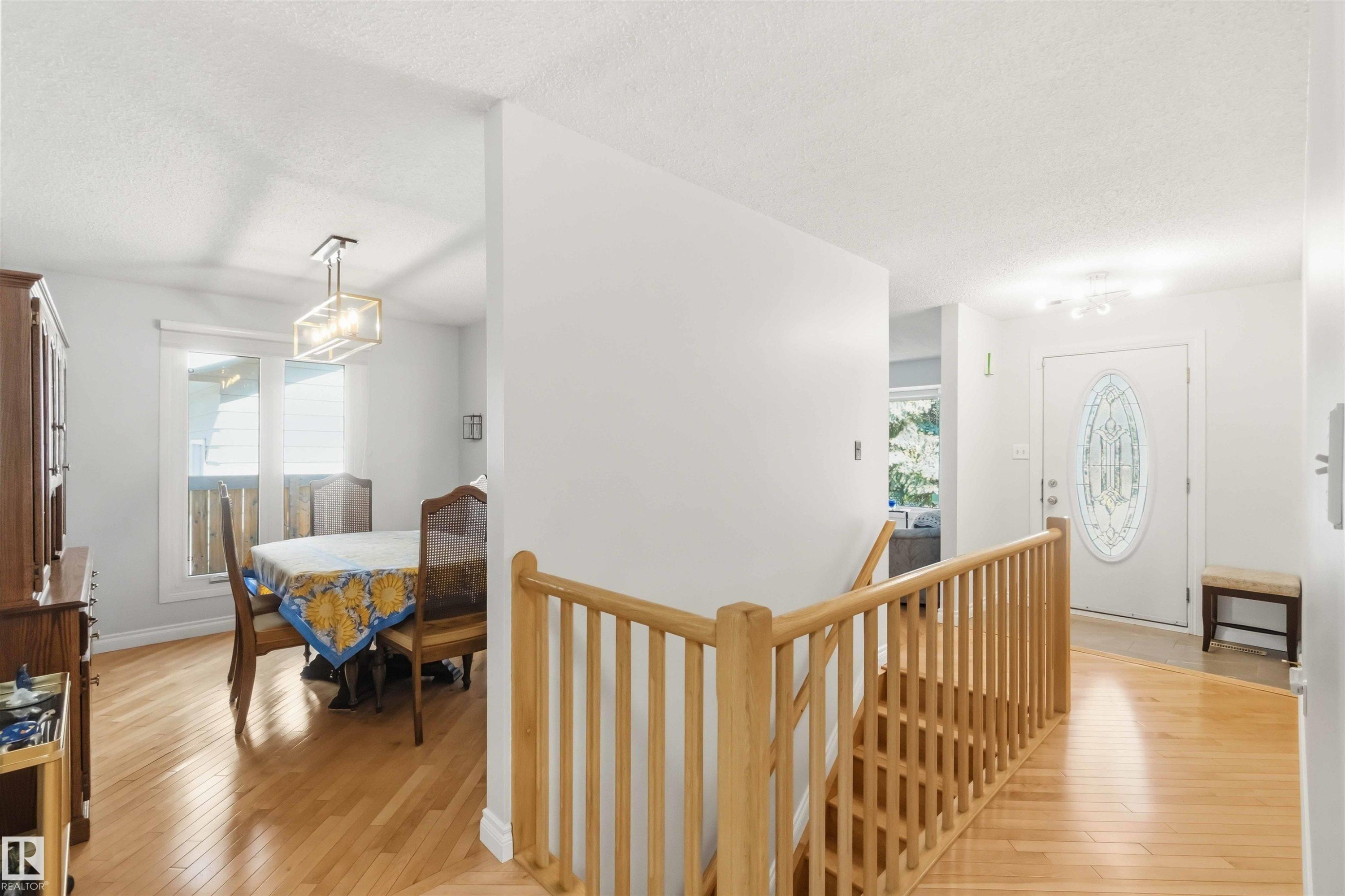 Bright entryway with wood-finish flooring extending into the dining area - 31 Gariepy Crescent, Edmonton, AB