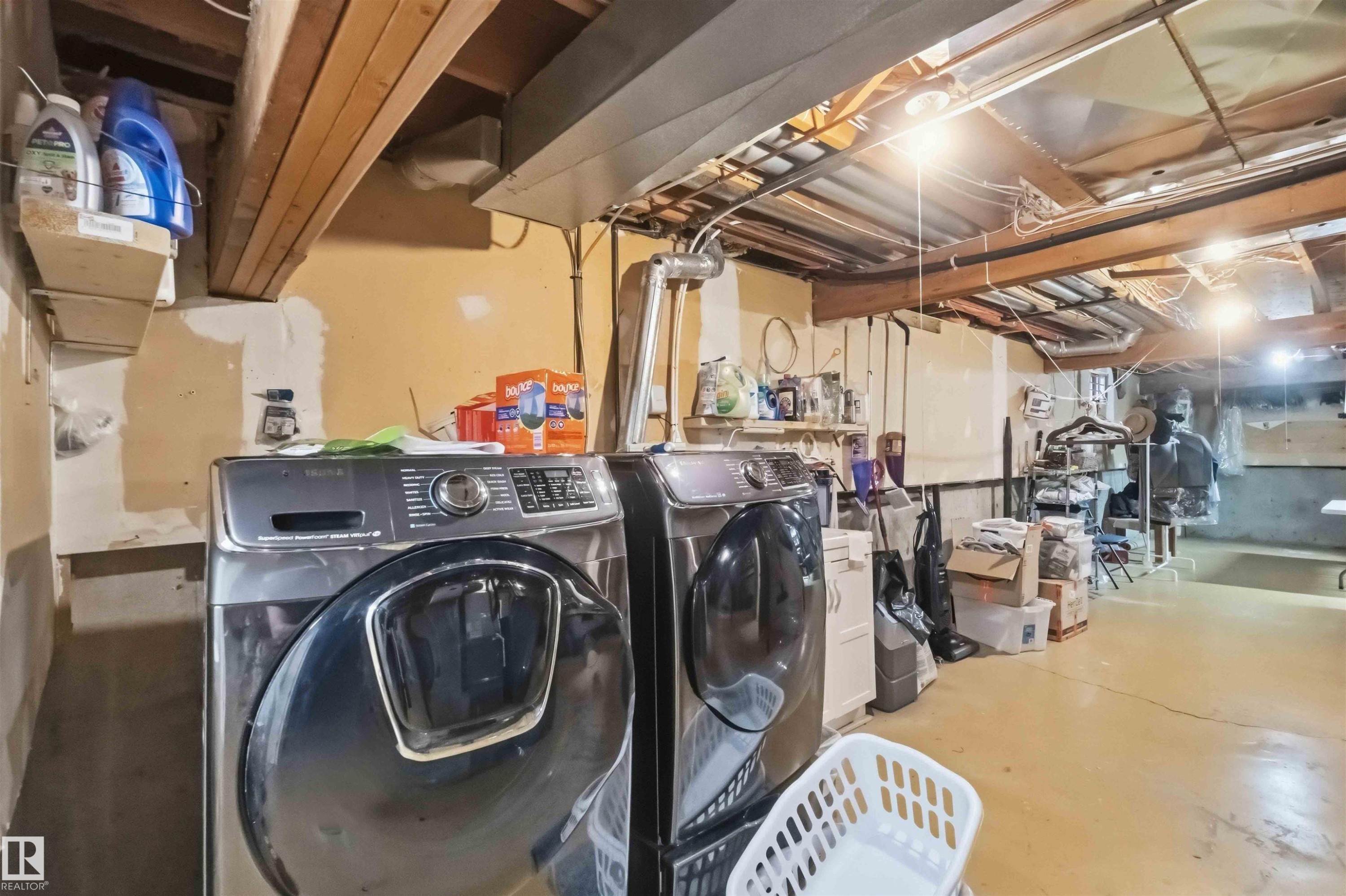 Laundry area featuring a side-by-side washer and dryer, exposed ceiling joists, and a concrete floor - 31 Gariepy Crescent, Edmonton, AB