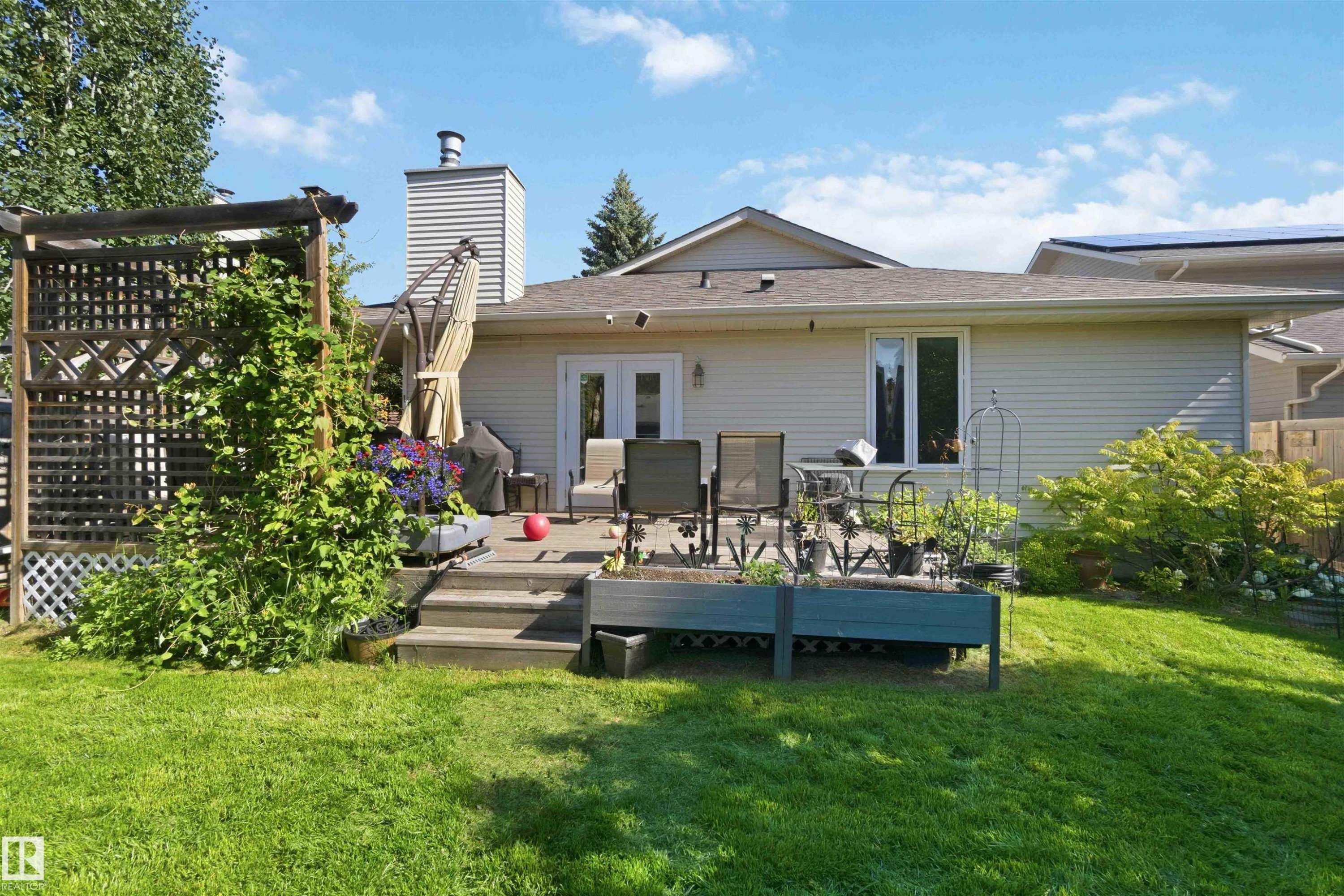Expansive backyard featuring a multi-level wooden deck with steps, a lattice pergola, and lush green lawn - 31 Gariepy Crescent, Edmonton, AB