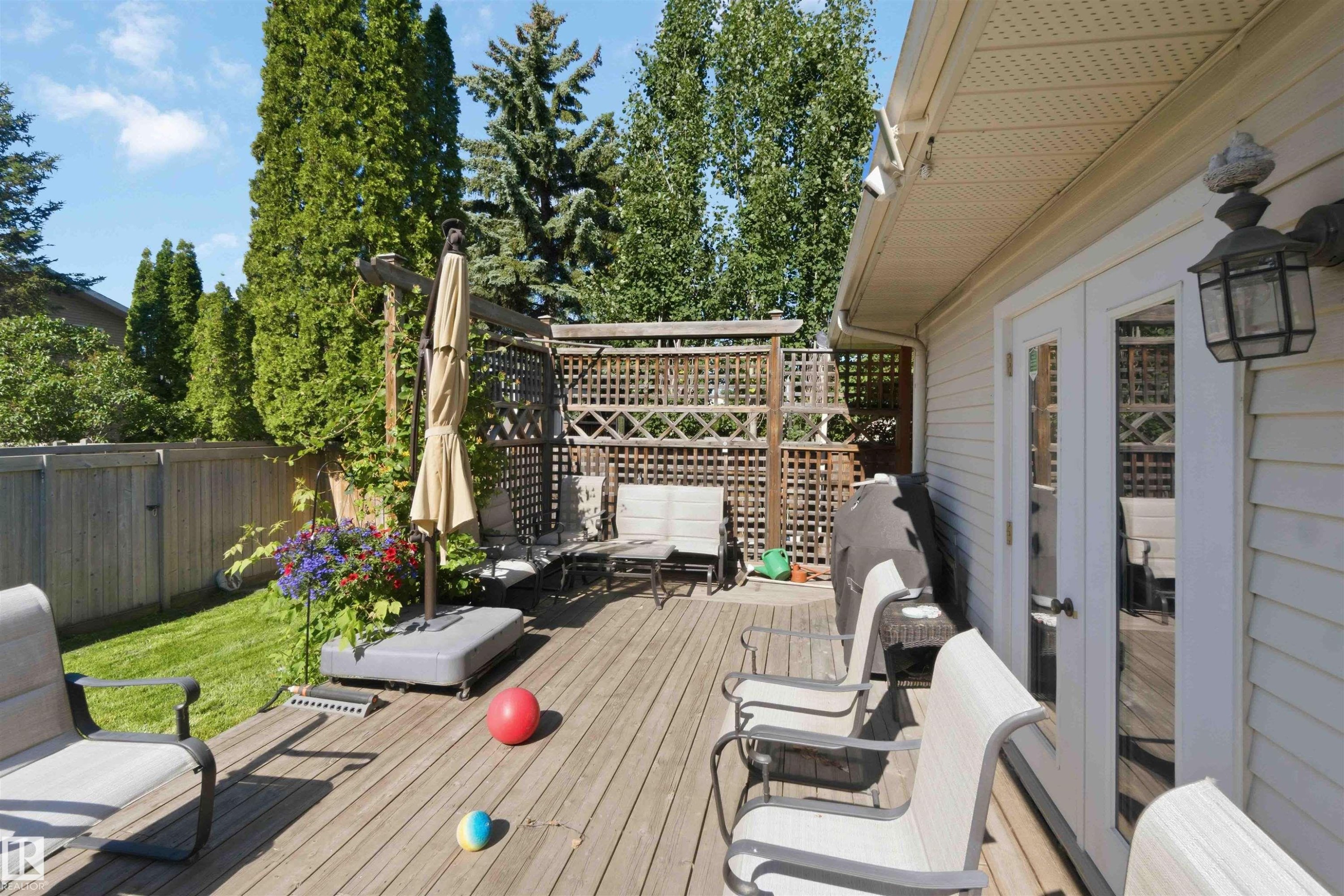 Expansive wood deck with a privacy lattice, offering direct access to the interior via double French doors - 31 Gariepy Crescent, Edmonton, AB