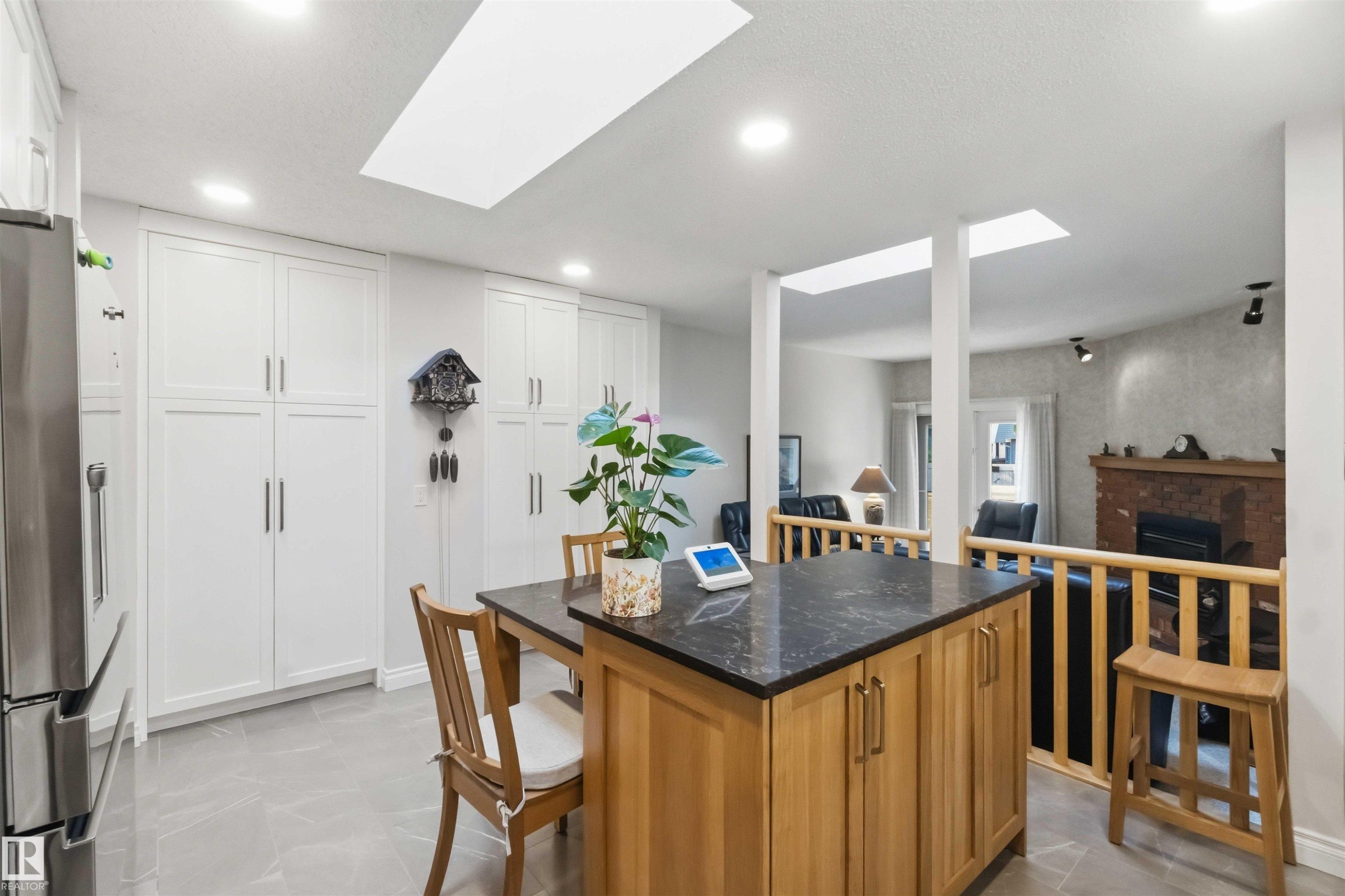 Kitchen island with wood-finish cabinetry, dark countertop, and integrated seating - 31 Gariepy Crescent, Edmonton, AB