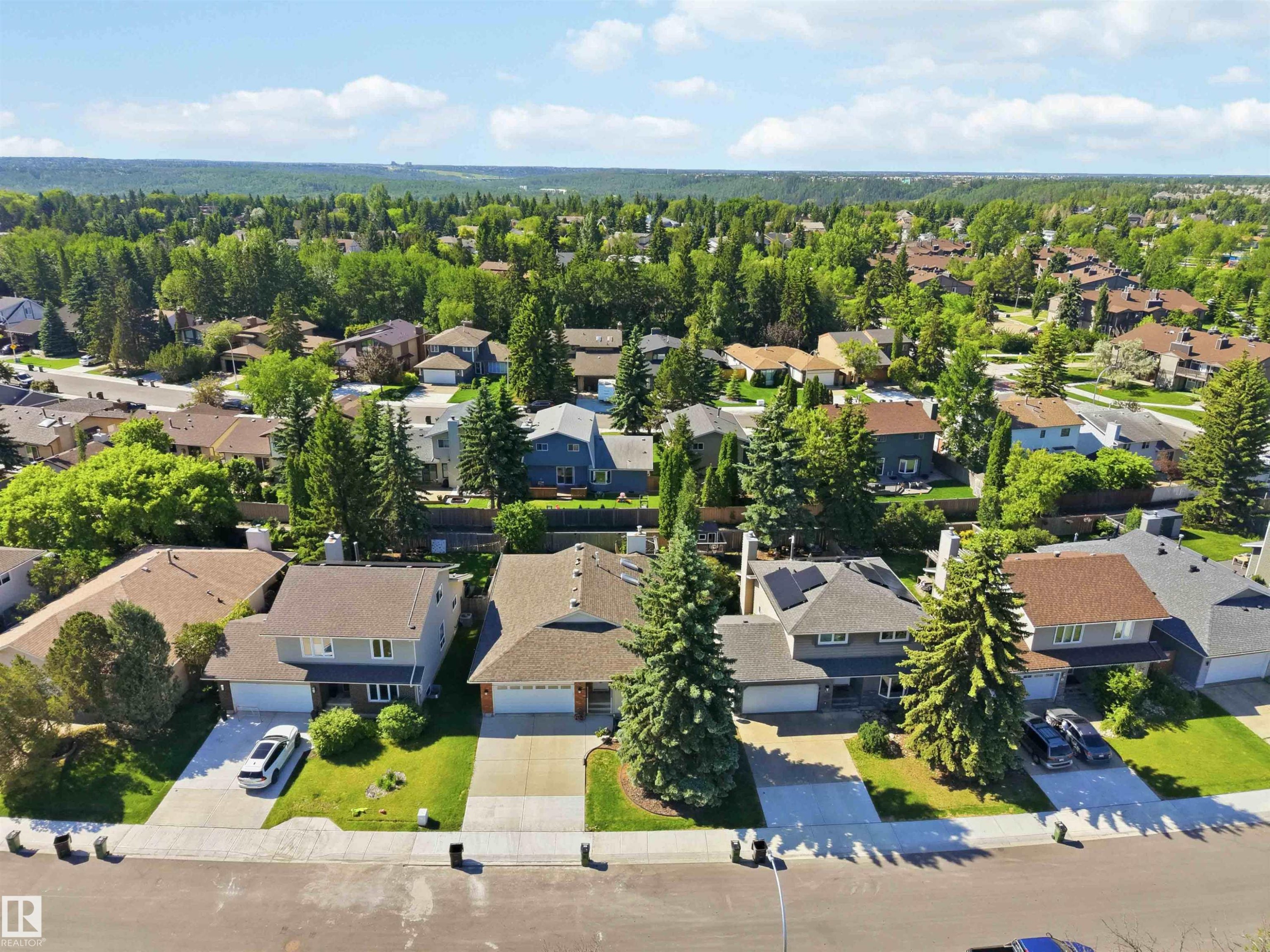Aerial perspective showcasing a residential neighborhood with diverse housing styles, mature trees, and paved streets - 31 Gariepy Crescent, Edmonton, AB