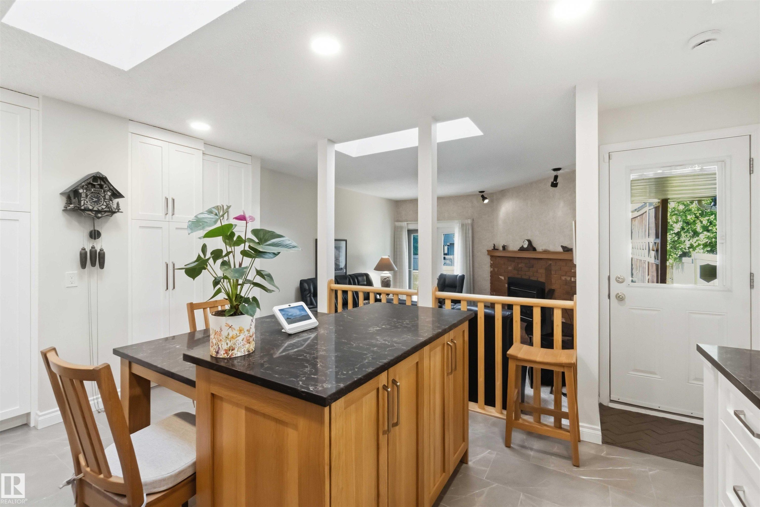 Kitchen featuring a central island with a dark countertop and natural wood cabinetry - 31 Gariepy Crescent, Edmonton, AB