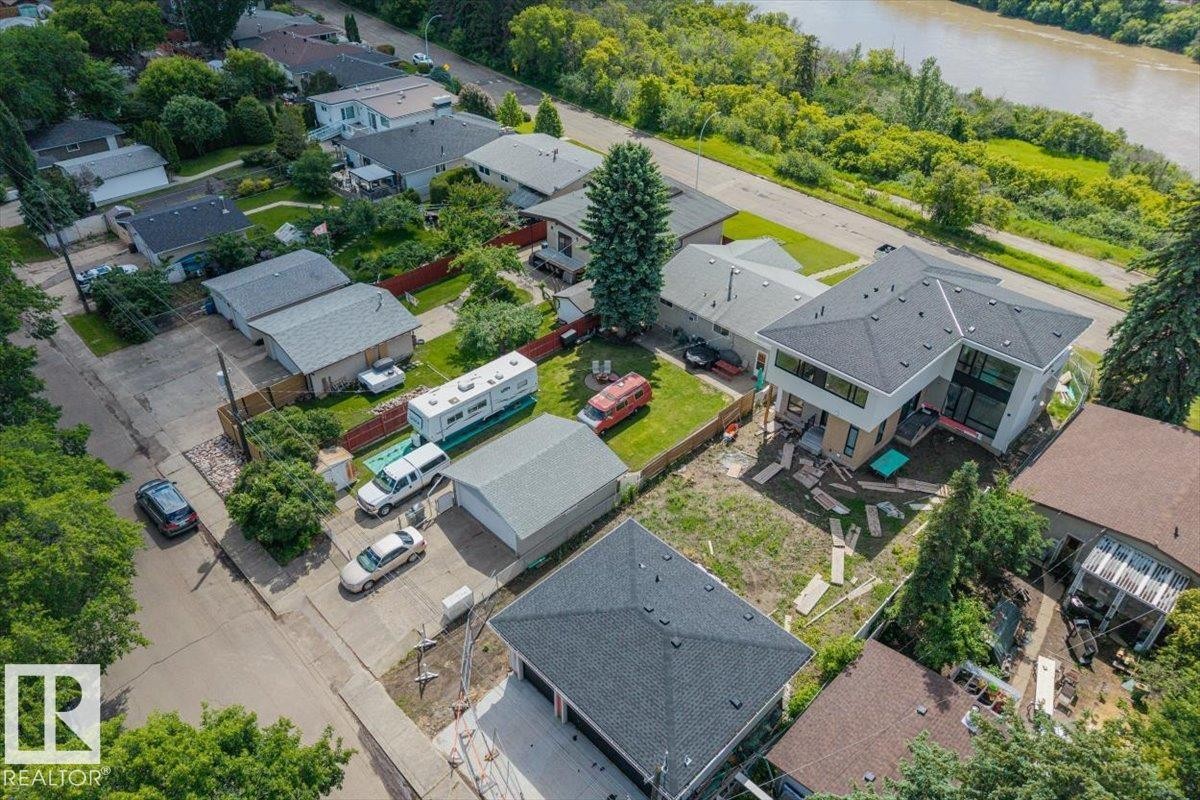 Modern multi-level residence featuring a dark shingle roof, extensive window lines, and a light-toned exterior - 4622 Ada Boulevard Nw, Edmonton, AB - Outdoor With Body Of Water With View