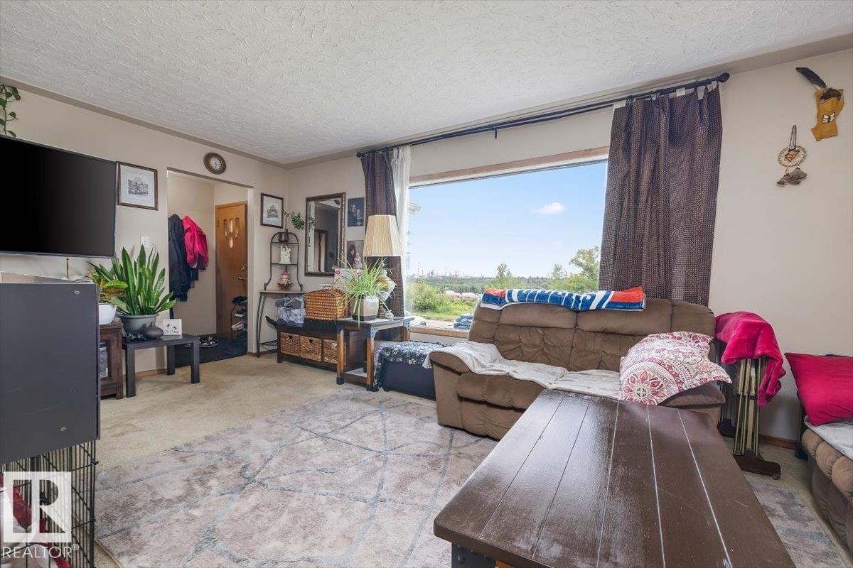 Living room featuring a large picture window, textured ceiling, and light-colored carpeting - 4622 Ada Boulevard Nw, Edmonton, AB - Indoor Photo Showing Living Room