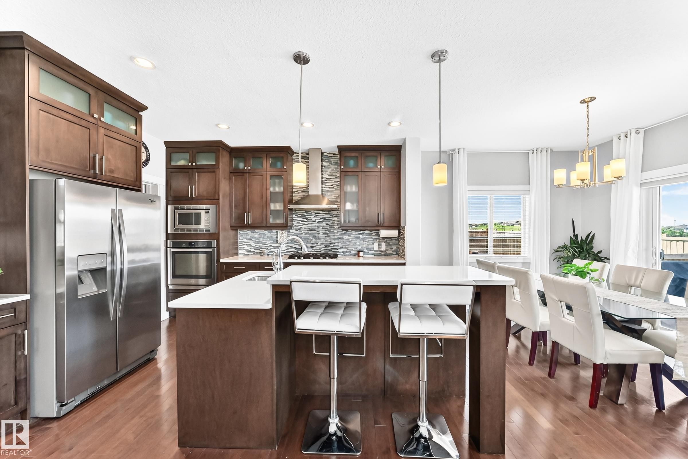 Kitchen featuring a center island with seating, stainless steel appliances, wood-finish flooring, and recessed lighting - 3672 Claxton Place Sw, Edmonton, AB