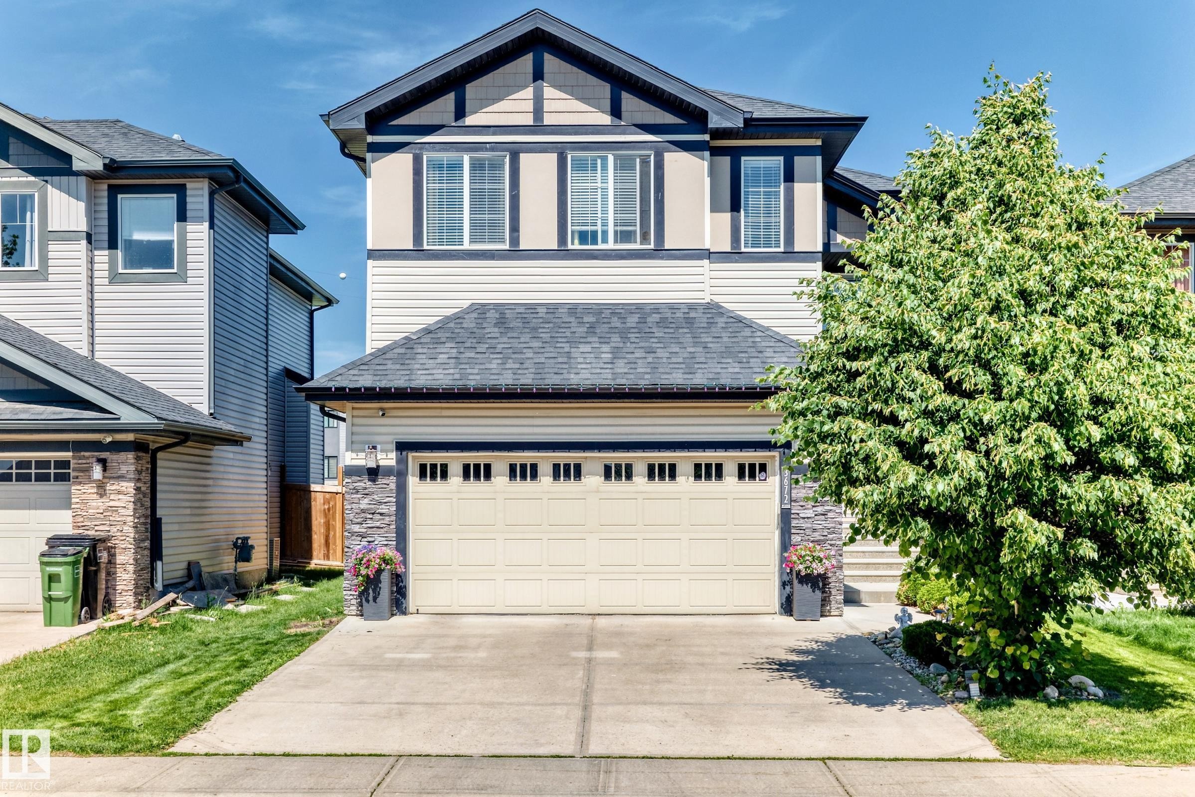 Contemporary two-story exterior featuring a light-toned siding, stone accents, and a dark shingle roof - 3672 Claxton Place Sw, Edmonton, AB