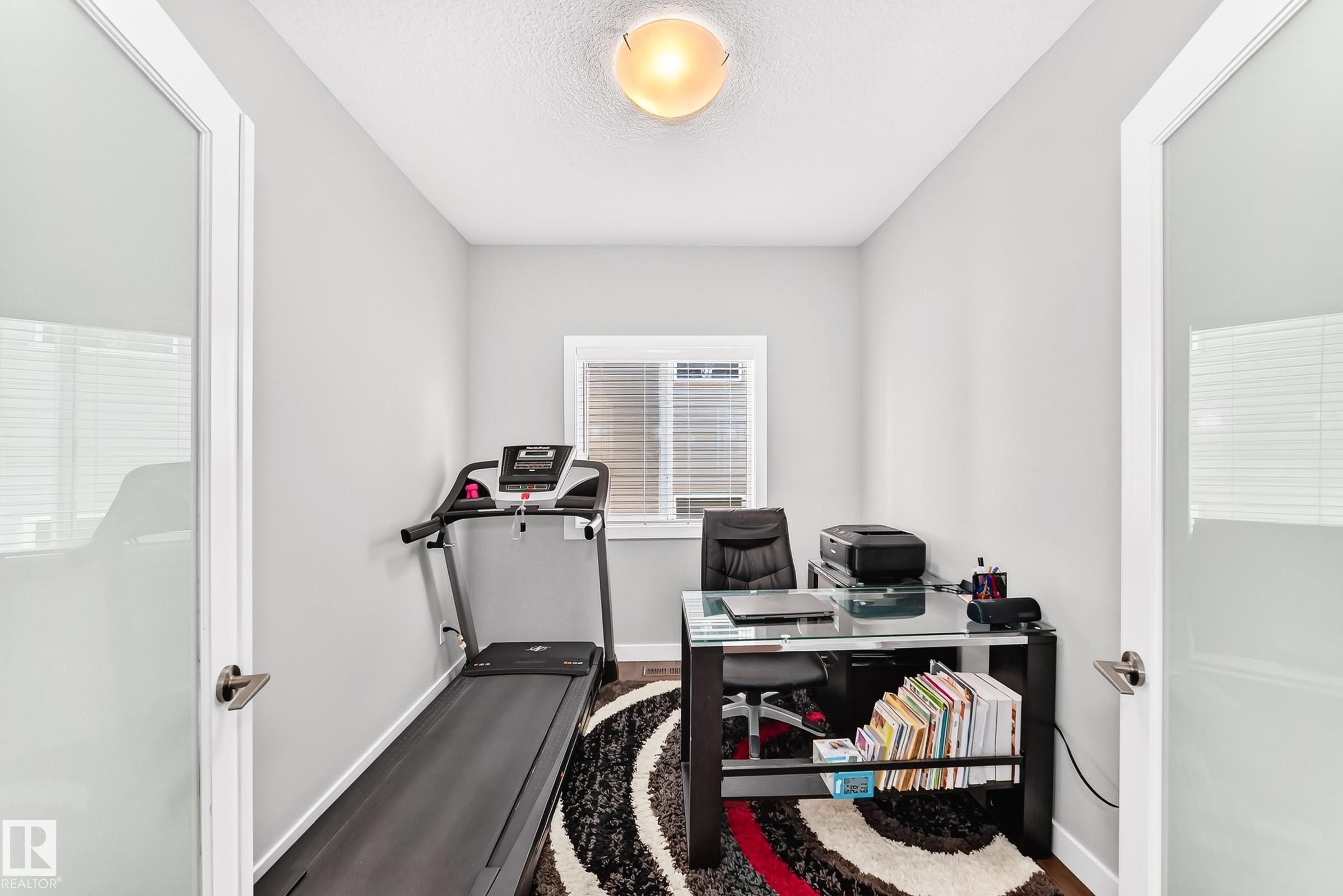 Compact room featuring wood-finish flooring, a window with horizontal blinds, and a ceiling-mounted light fixture - 3672 Claxton Place Sw, Edmonton, AB