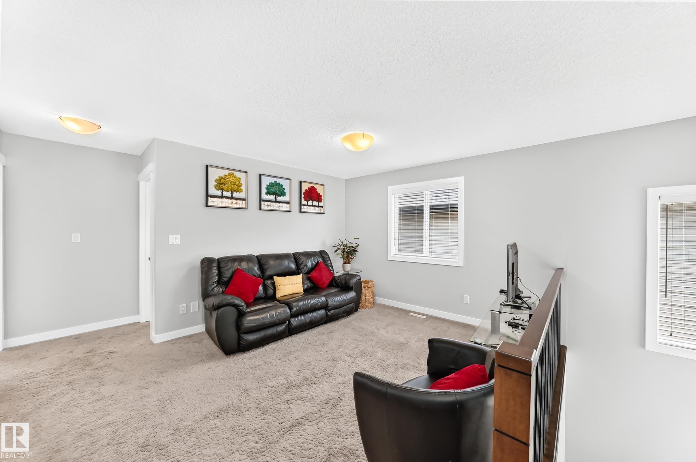 Carpeted room featuring light gray walls, white trim, and two flush-mount ceiling lights - 3672 Claxton Place Sw, Edmonton, AB