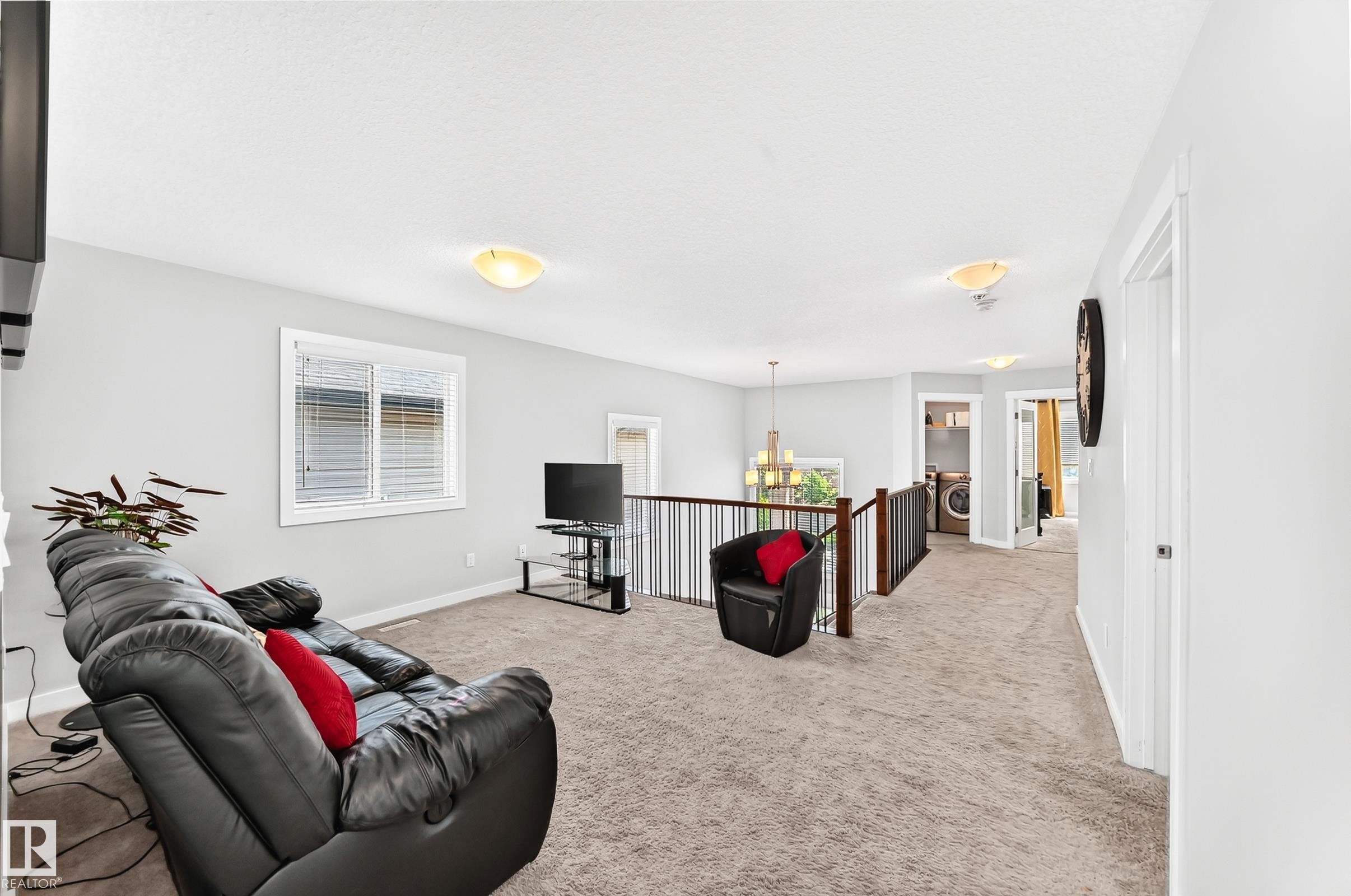 Open upper-level area featuring light-toned carpeting, a window with blinds, and white walls - 3672 Claxton Place Sw, Edmonton, AB