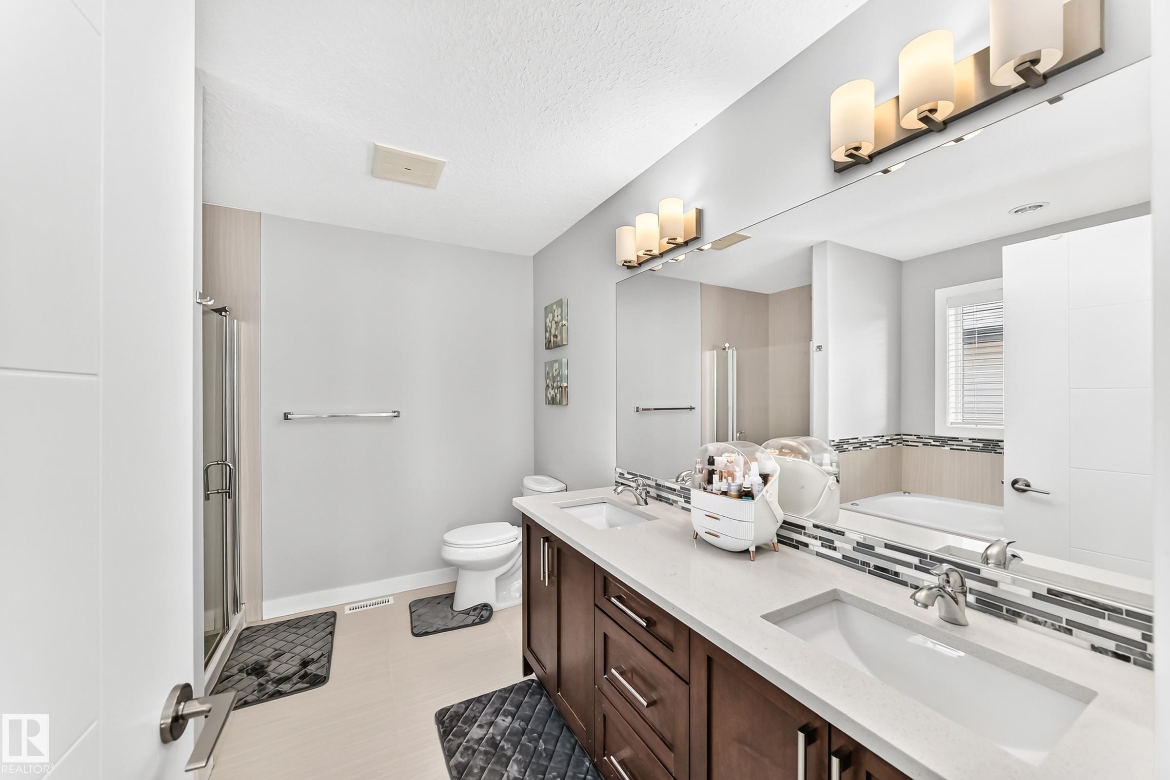 Bathroom featuring a dual vanity with a light countertop, dark wood-finish cabinetry, and contemporary vessel sinks - 3672 Claxton Place Sw, Edmonton, AB