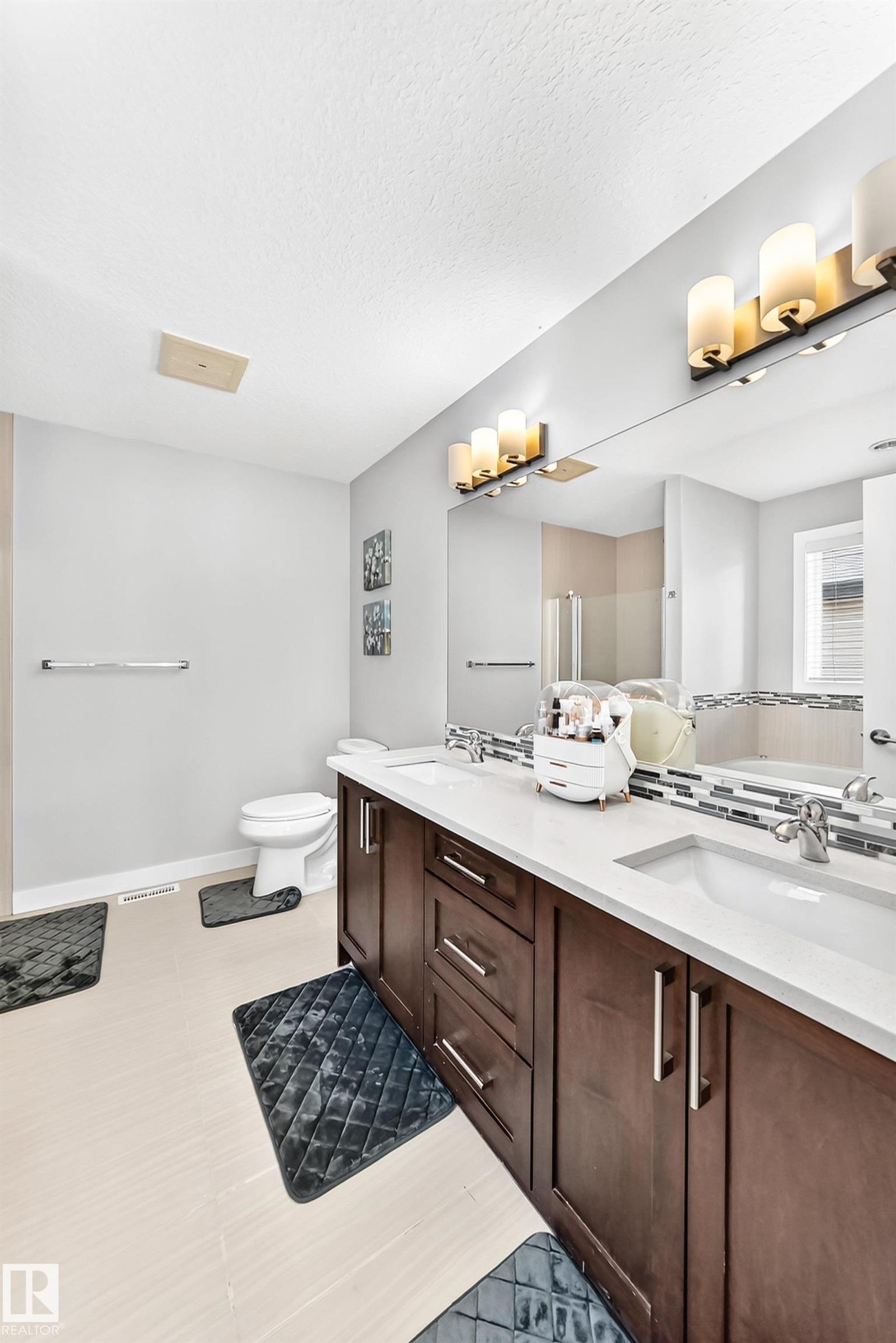 Bathroom featuring a dual vanity with dark wood-finish cabinetry, white countertops, and undermount sinks - 3672 Claxton Place Sw, Edmonton, AB