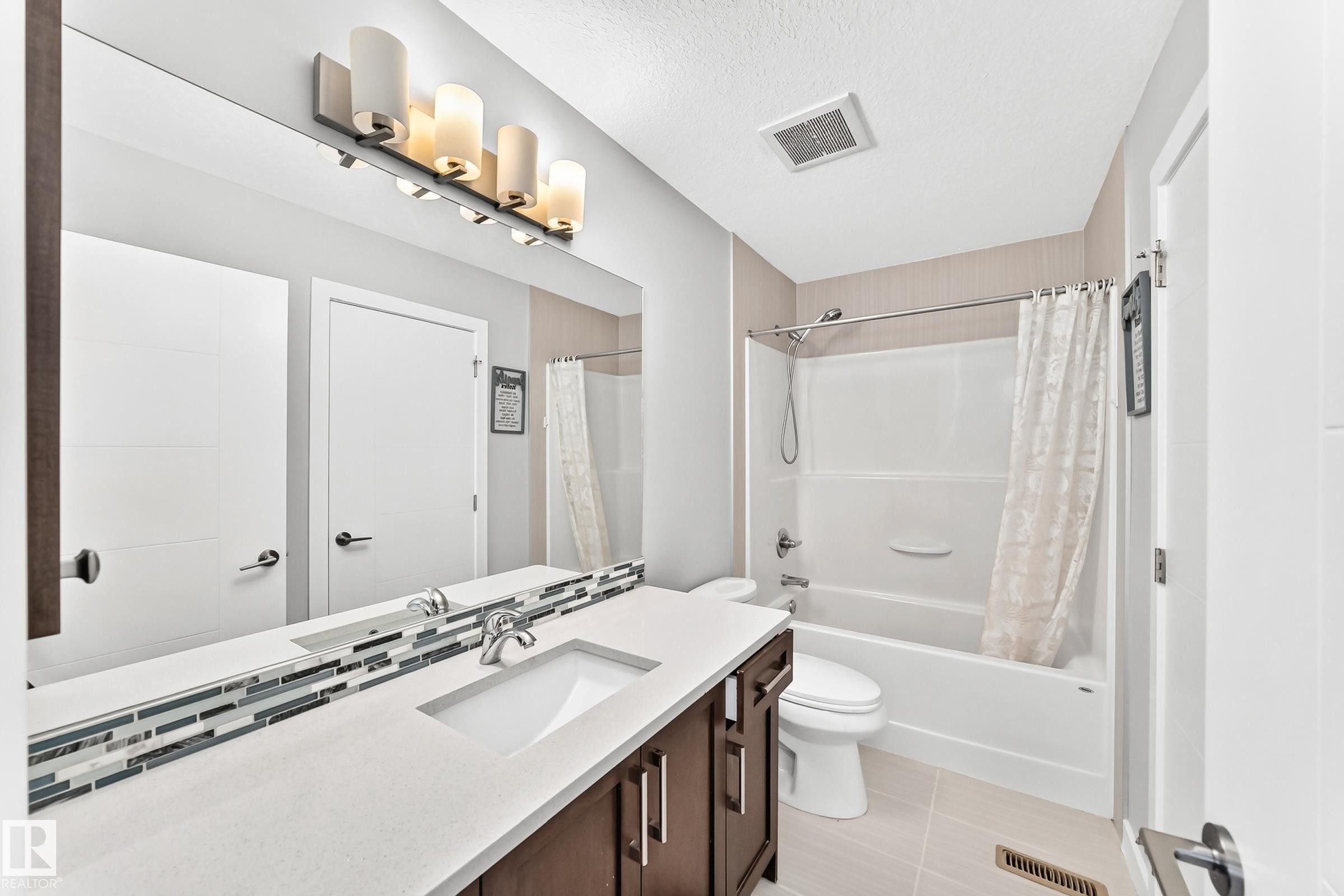 Bathroom vanity with a white rectangular sink, a light-toned countertop, and a dark wood-finish cabinet - 3672 Claxton Place Sw, Edmonton, AB
