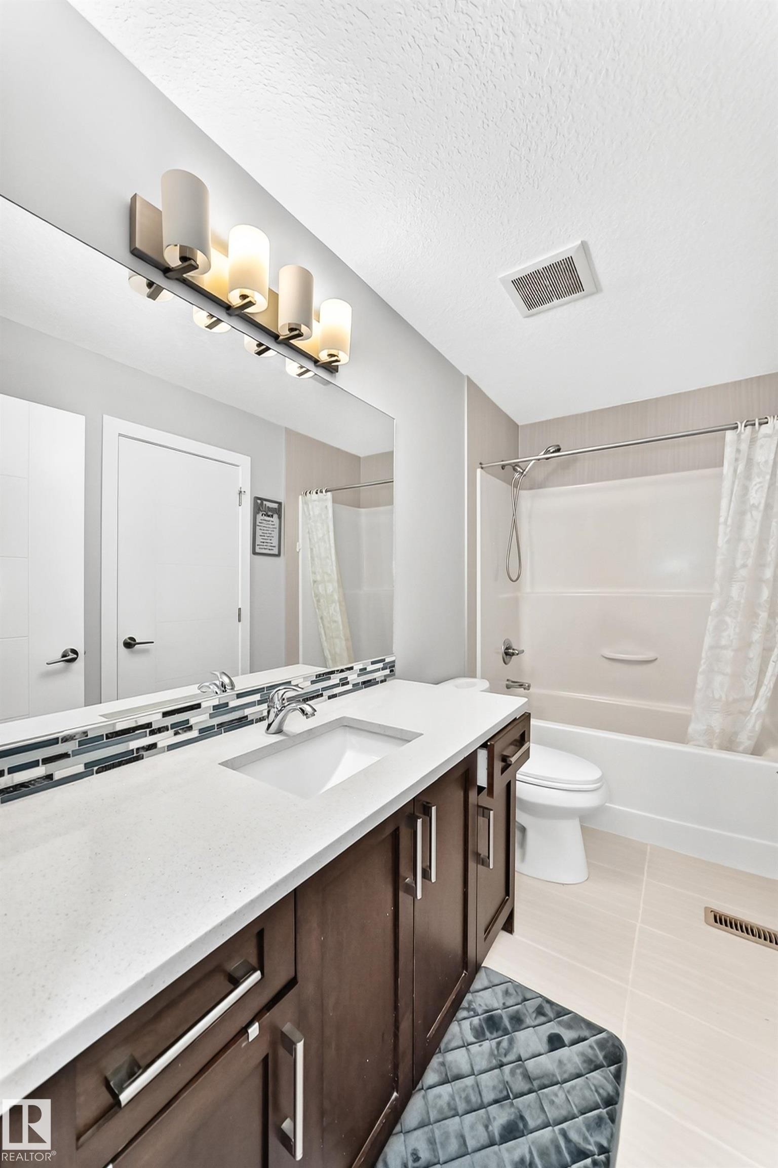 Full bathroom featuring a dark wood-finish vanity with a white countertop and undermount sink - 3672 Claxton Place Sw, Edmonton, AB