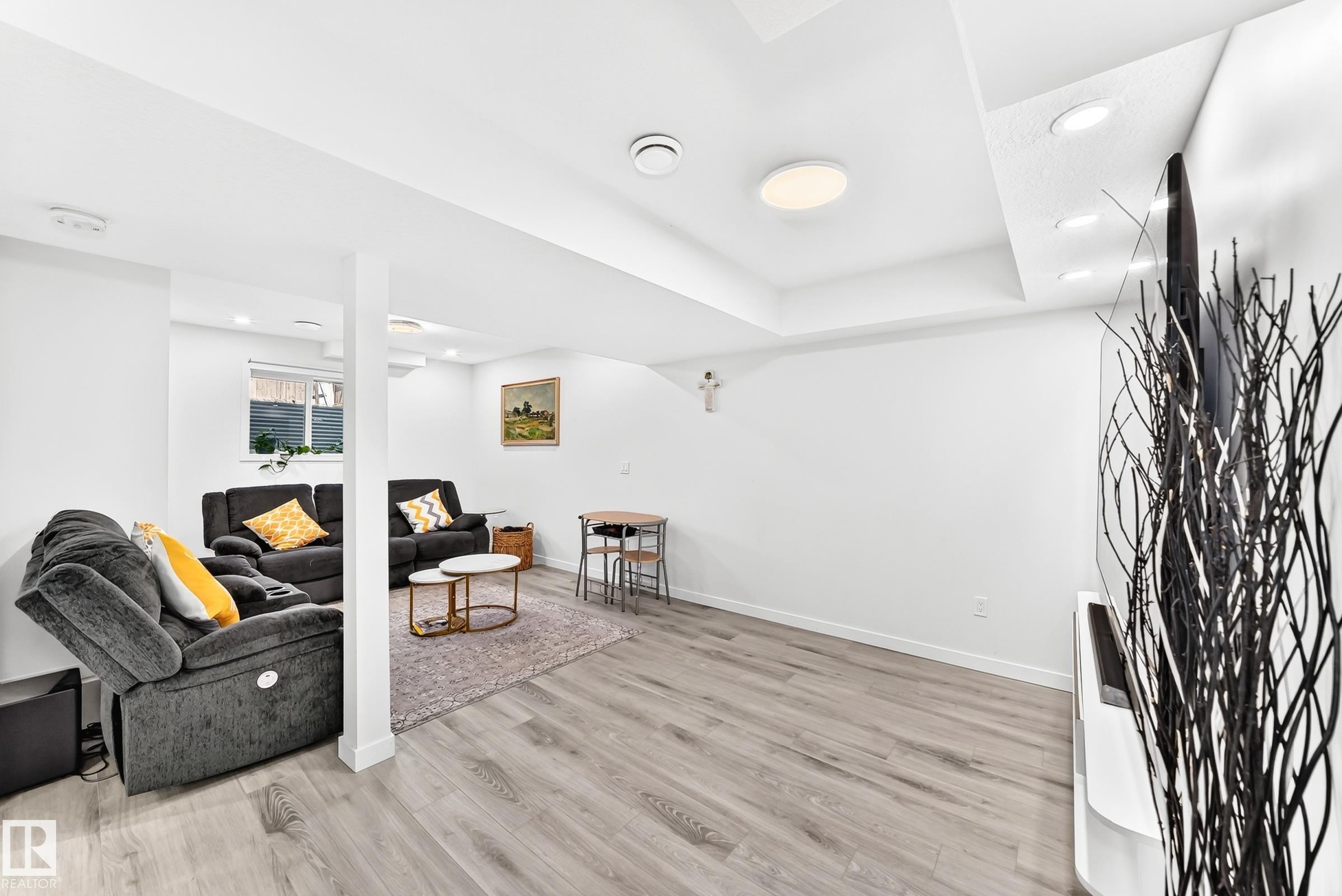 Open-concept living area featuring light wood-finish flooring, recessed ceiling lighting, and a neutral color palette - 3672 Claxton Place Sw, Edmonton, AB