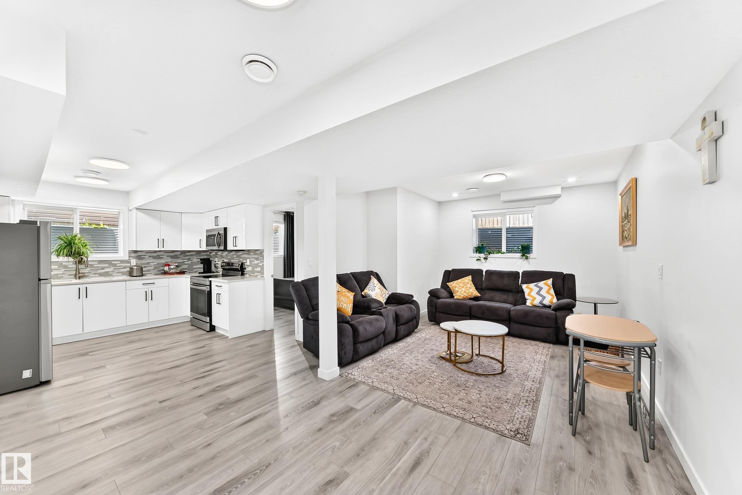 Open-concept living space featuring wood-finish flooring, recessed lighting, and a white color palette - 3672 Claxton Place Sw, Edmonton, AB