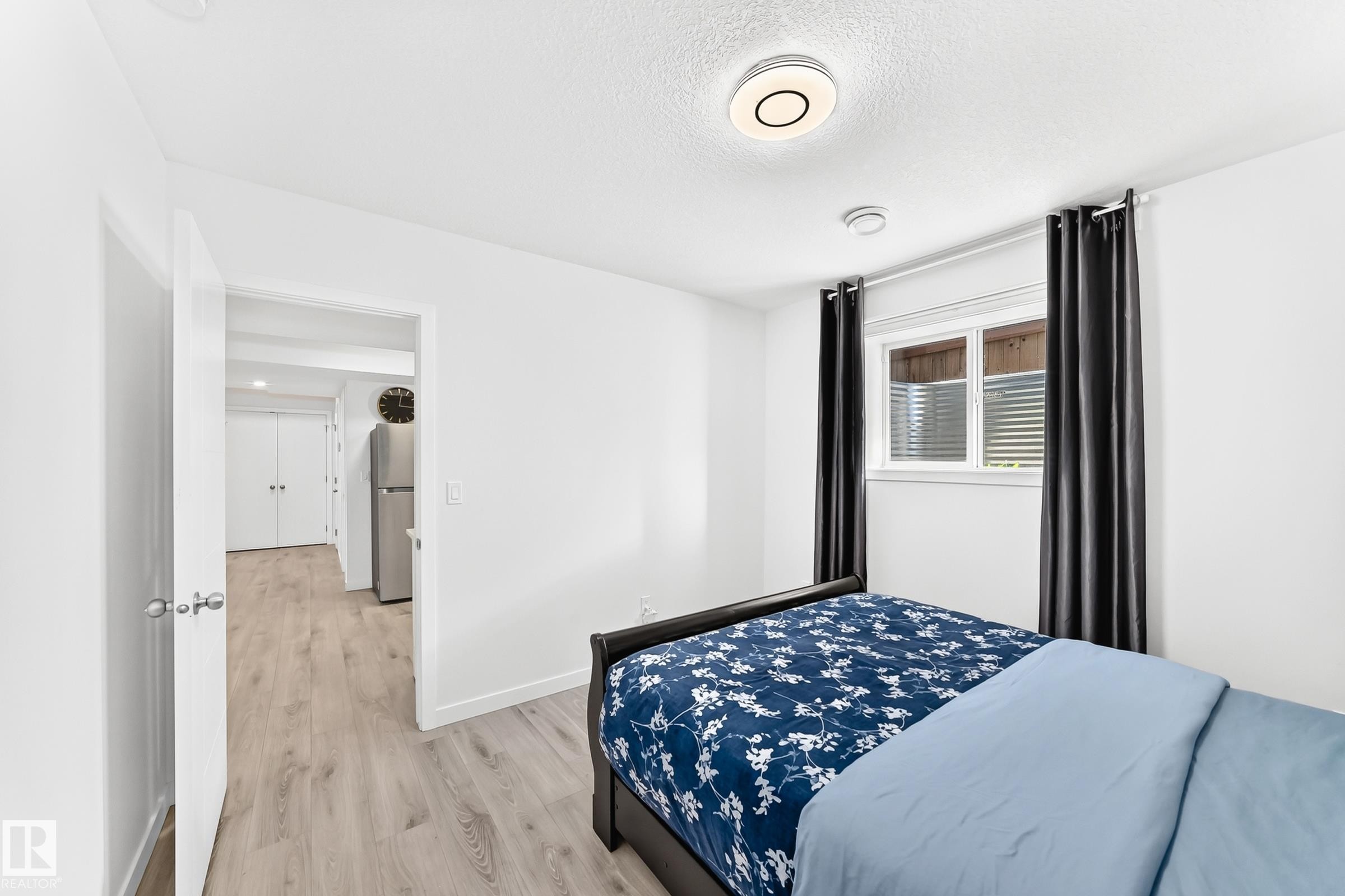Bright bedroom featuring white walls, wood-finish flooring, a window with horizontal blinds, and recessed lighting - 3672 Claxton Place Sw, Edmonton, AB