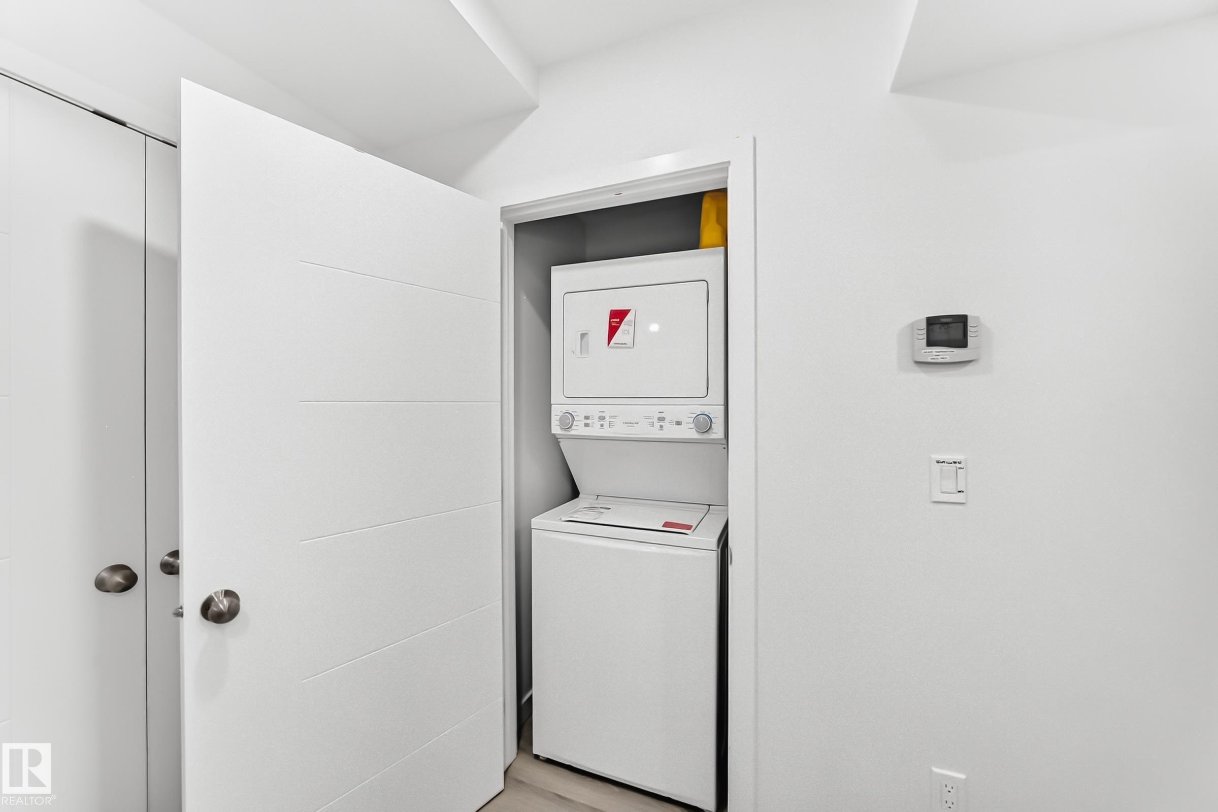 Dedicated laundry closet featuring a stacked washer and dryer unit - 3672 Claxton Place Sw, Edmonton, AB