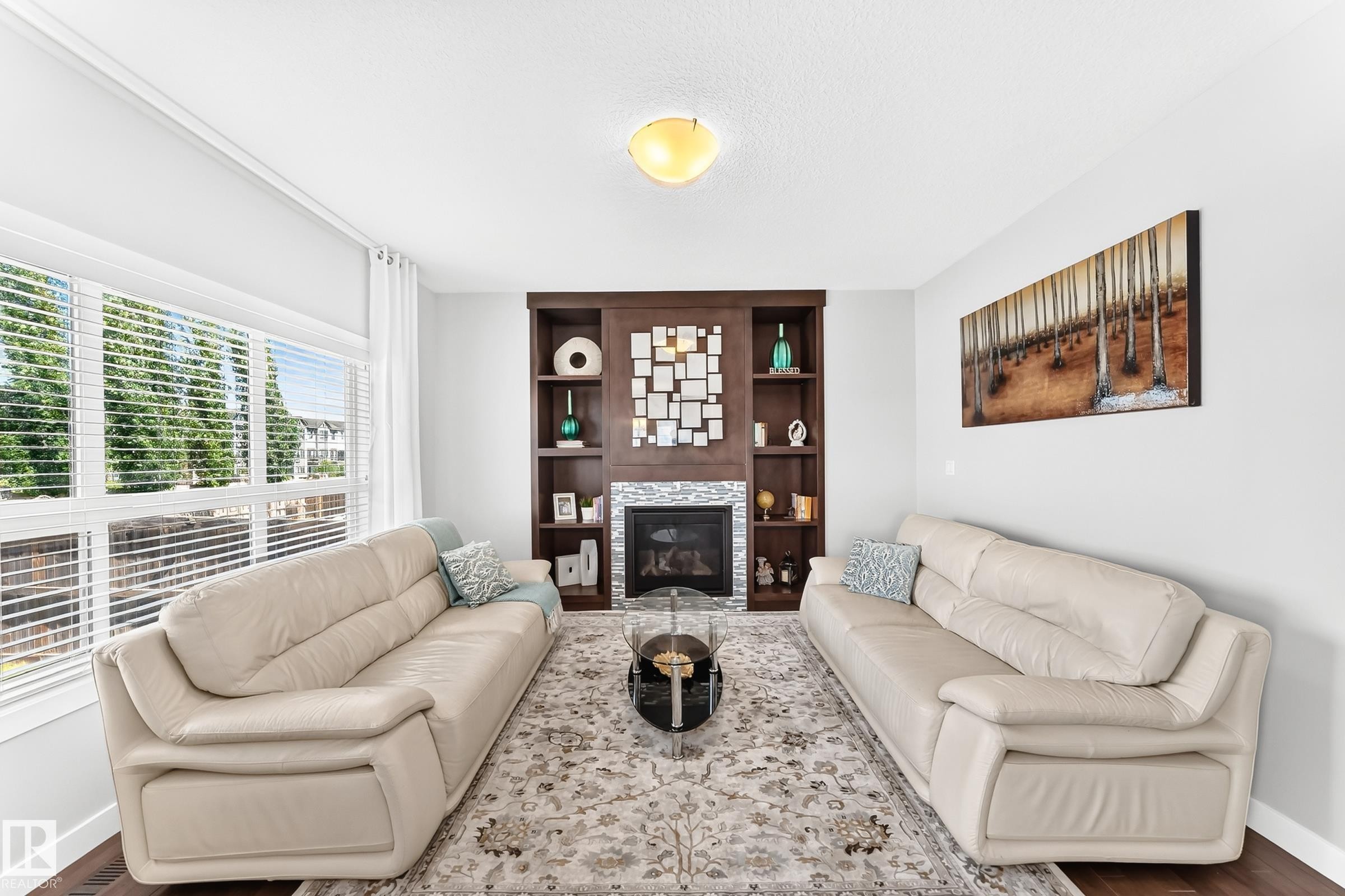 Living area featuring a floor-to-ceiling built-in fireplace with a stone surround and dark wood shelving - 3672 Claxton Place Sw, Edmonton, AB