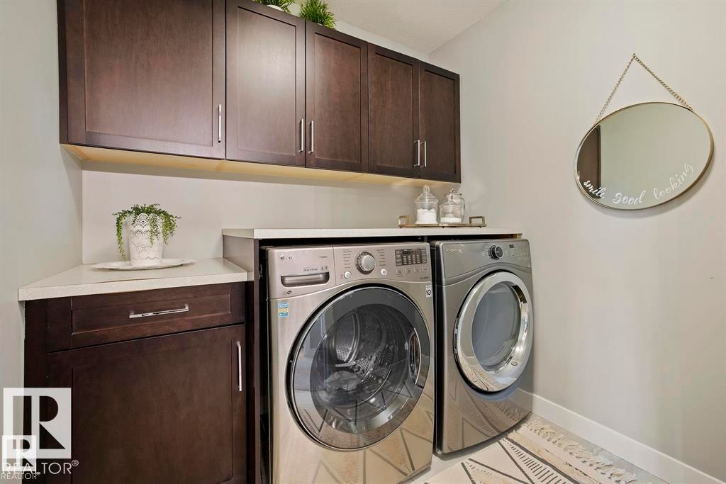 Laundry area featuring stacked front-load machines, dark wood-finish cabinetry with brushed nickel hardware, and light-toned countertops - 1004 Huckell Pl Sw, Edmonton, AB - Indoor Photo Showing Laundry Room