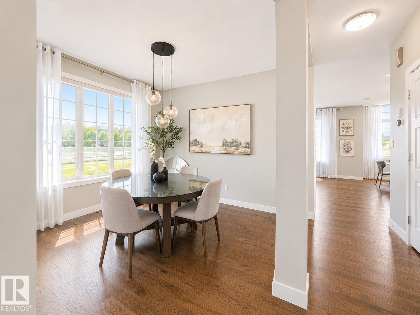Dining area featuring a large window, dark wood-finish flooring, a modern pendant light fixture, light gray wall paint, and white trim - 1004 Huckell Pl Sw, Edmonton, AB - Indoor Photo Showing Dining Room