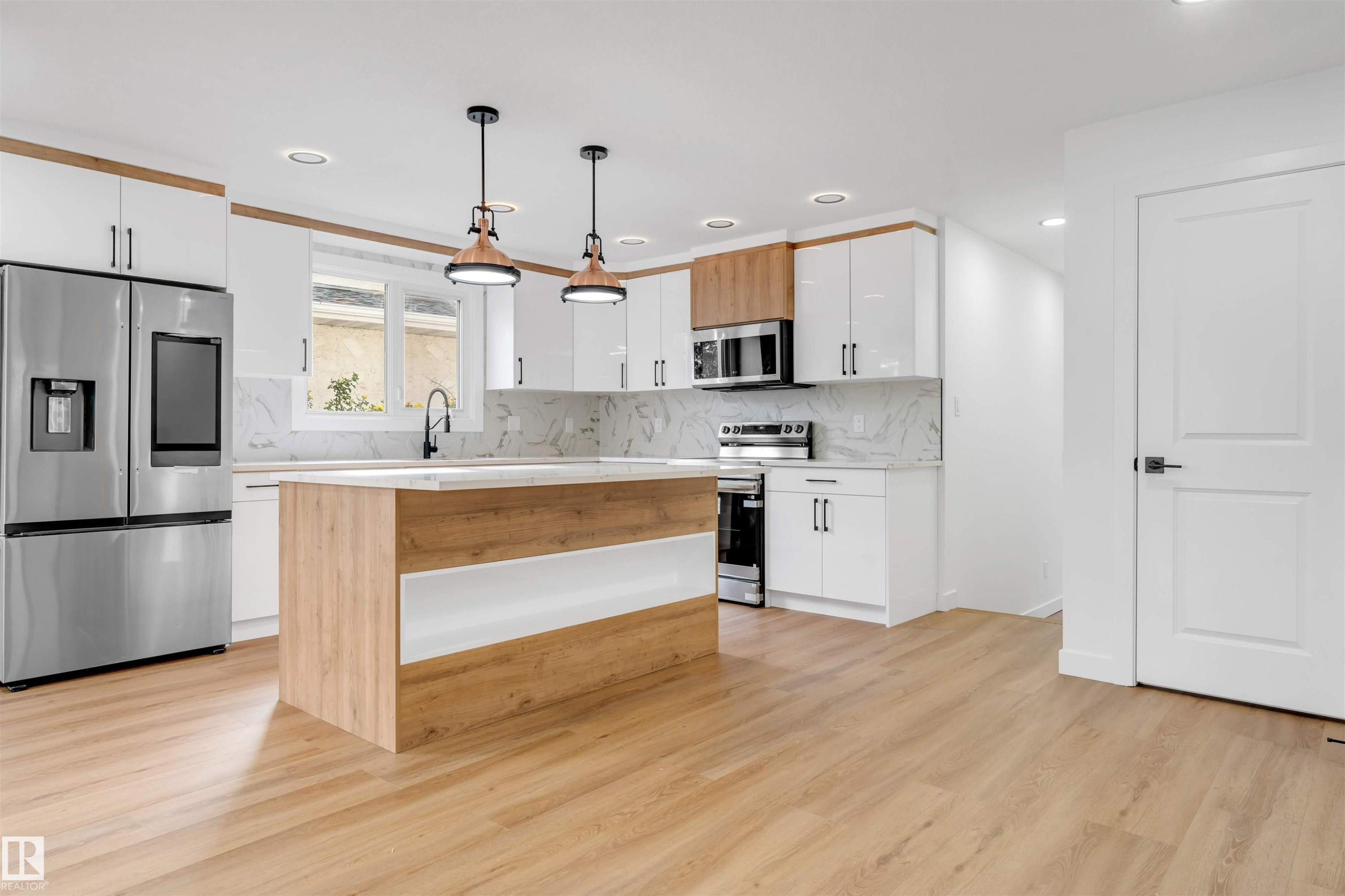 Kitchen featuring an island with wood-finish and white paneling, stone countertops, stainless steel appliances, and wood-finish flooring - 5512 150 Avenue, Edmonton, AB