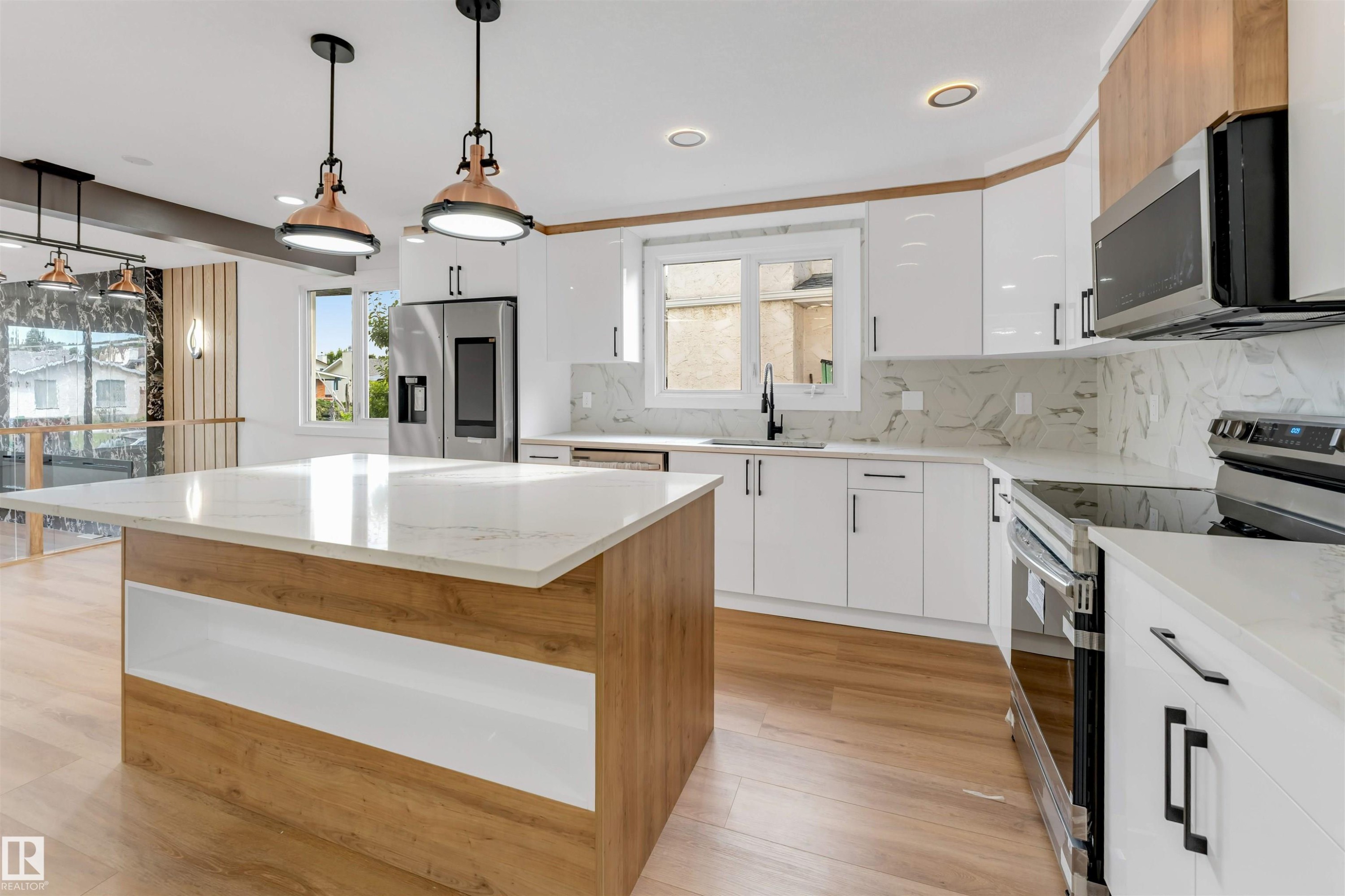 Modern kitchen featuring a large central island with a light wood-finish base and white countertop - 5512 150 Avenue, Edmonton, AB