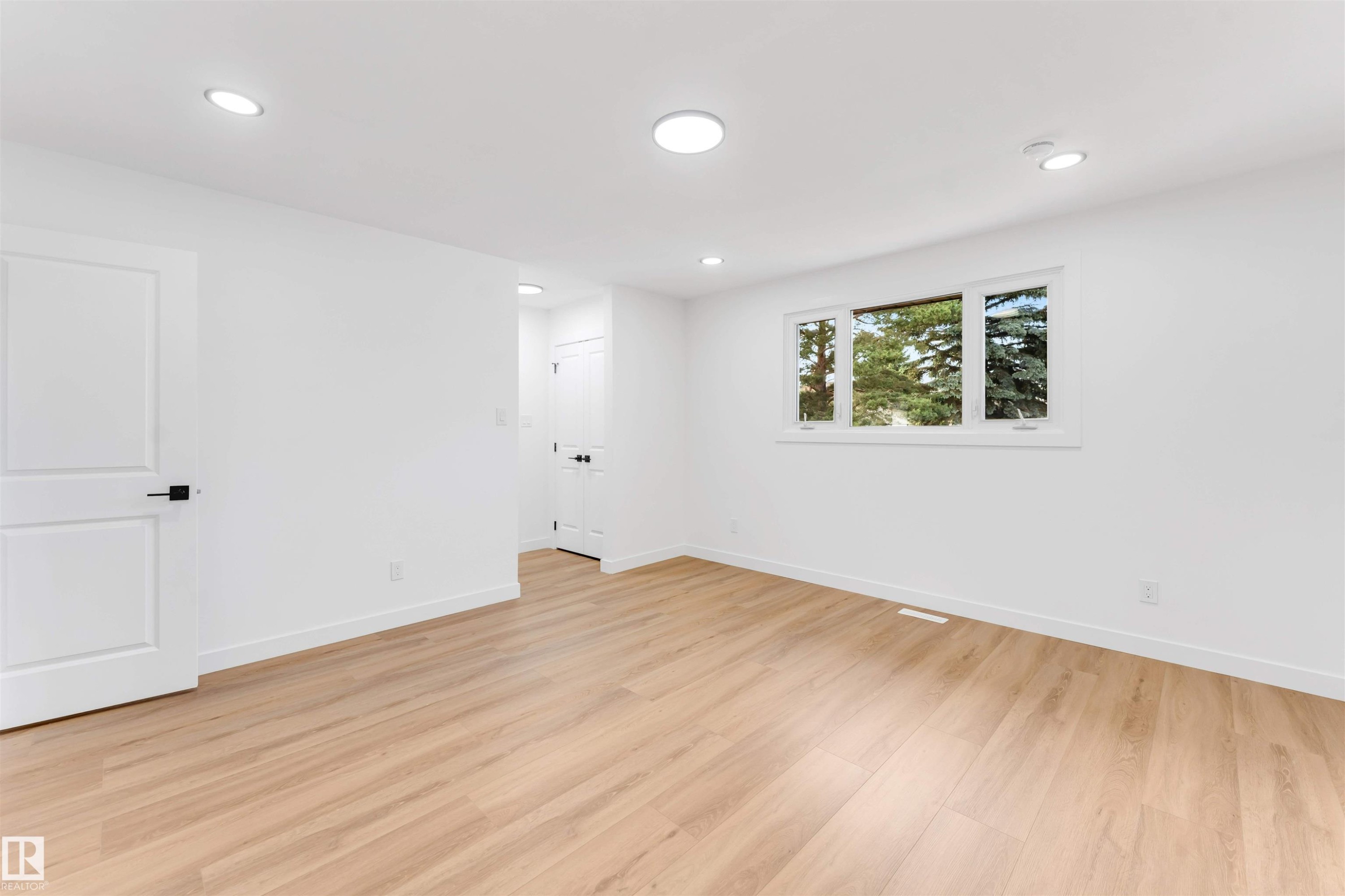 Bright interior space featuring wood-finish flooring, recessed lighting, and a white trim window - 5512 150 Avenue, Edmonton, AB