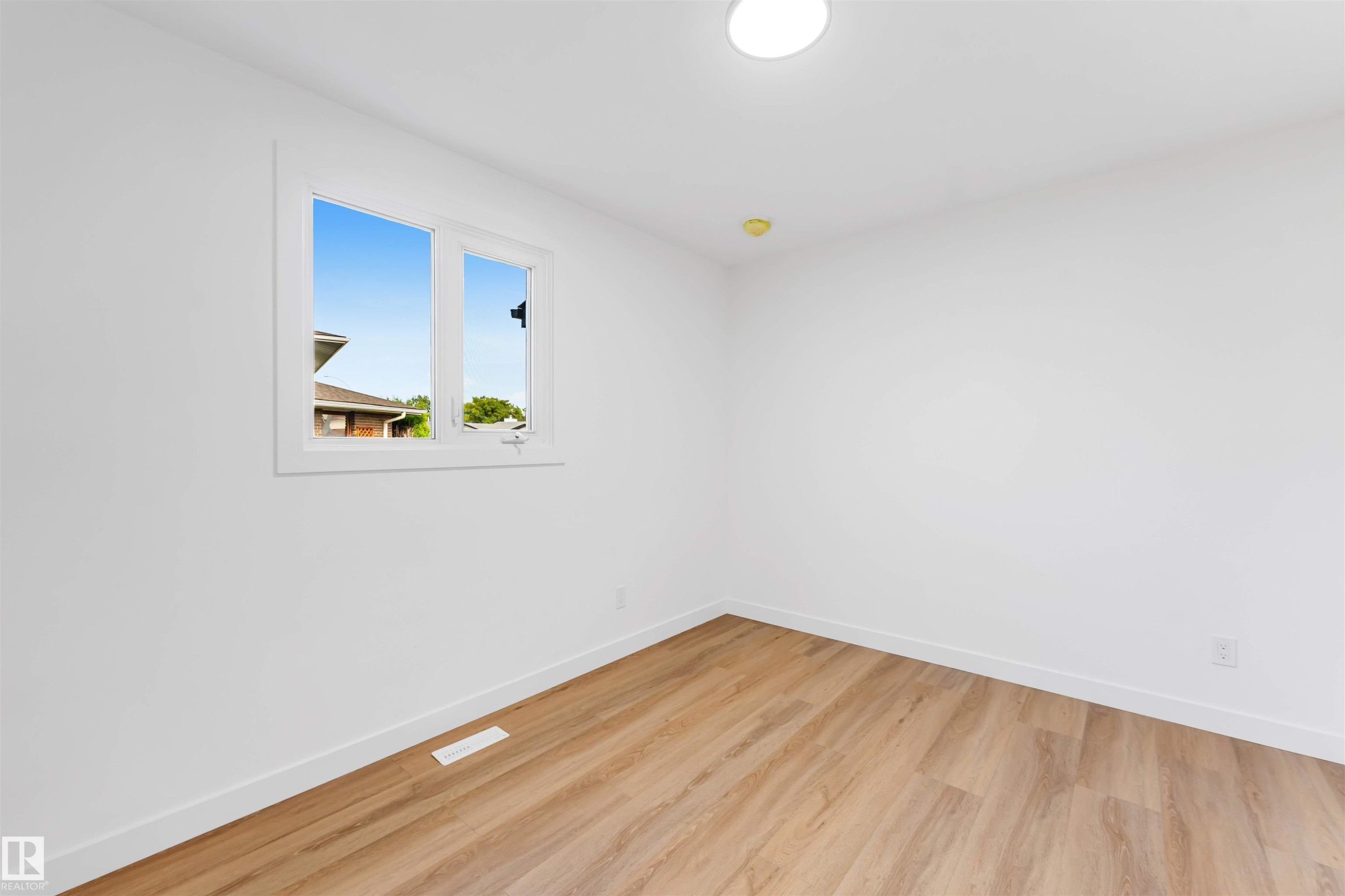 Bright room featuring wood-finish flooring, white walls, and white baseboards - 5512 150 Avenue, Edmonton, AB