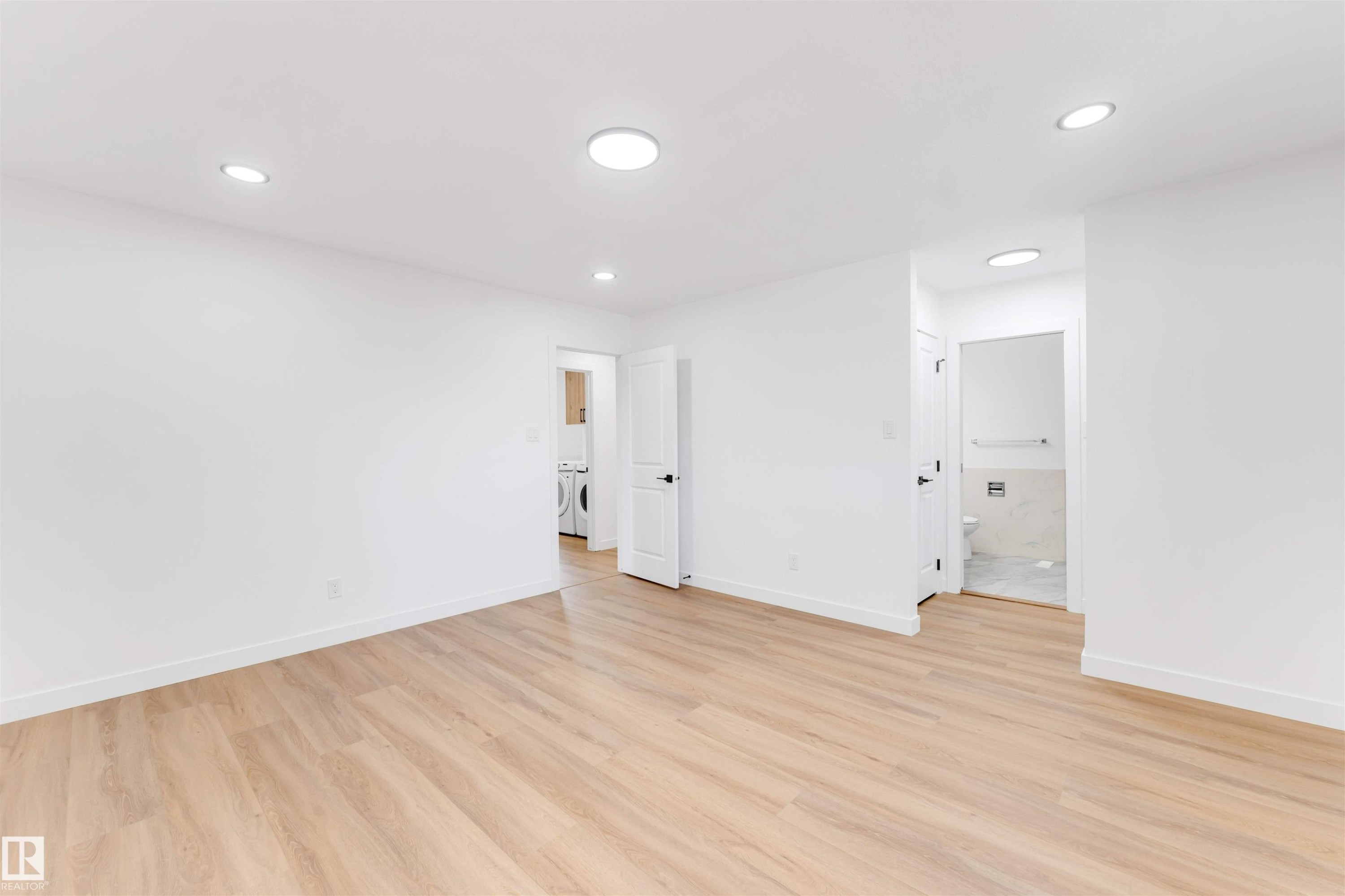 Spacious room featuring wood-finish flooring, recessed lighting, and bright white walls - 5512 150 Avenue, Edmonton, AB