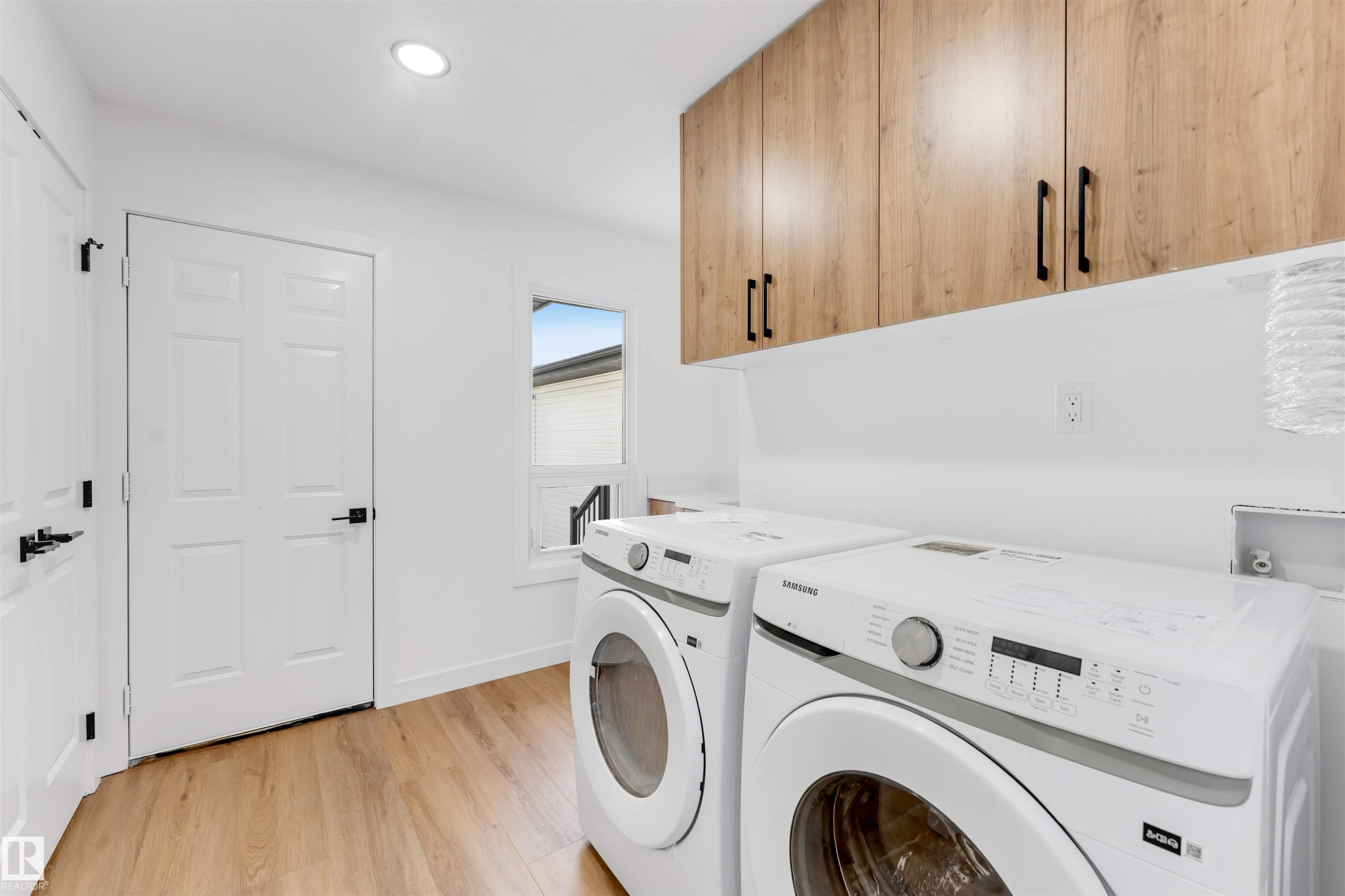 Laundry area featuring wood-finish flooring, white walls, and recessed lighting - 5512 150 Avenue, Edmonton, AB