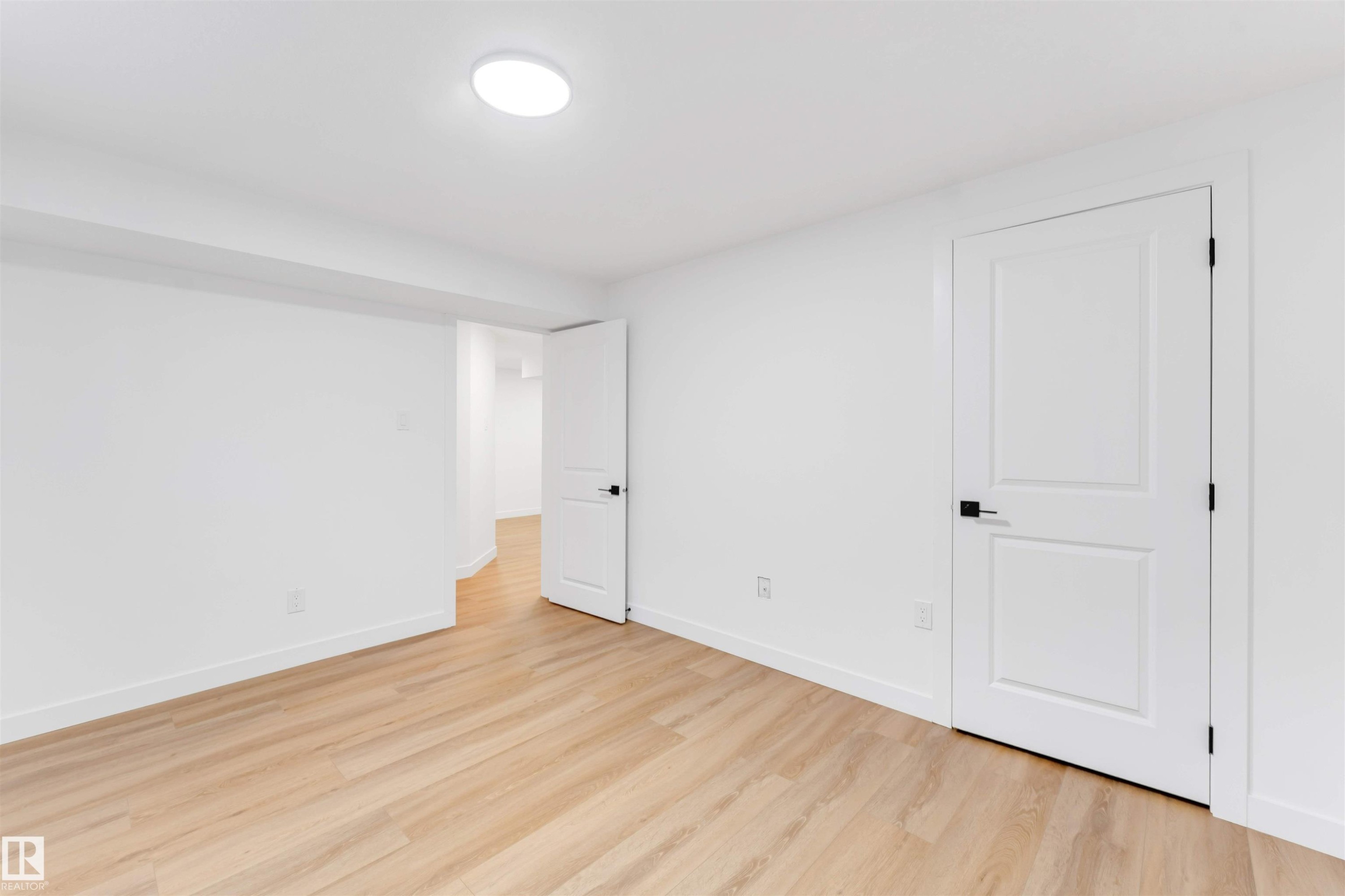 Room featuring wood-finish flooring, crisp white walls, and a recessed ceiling light - 5512 150 Avenue, Edmonton, AB