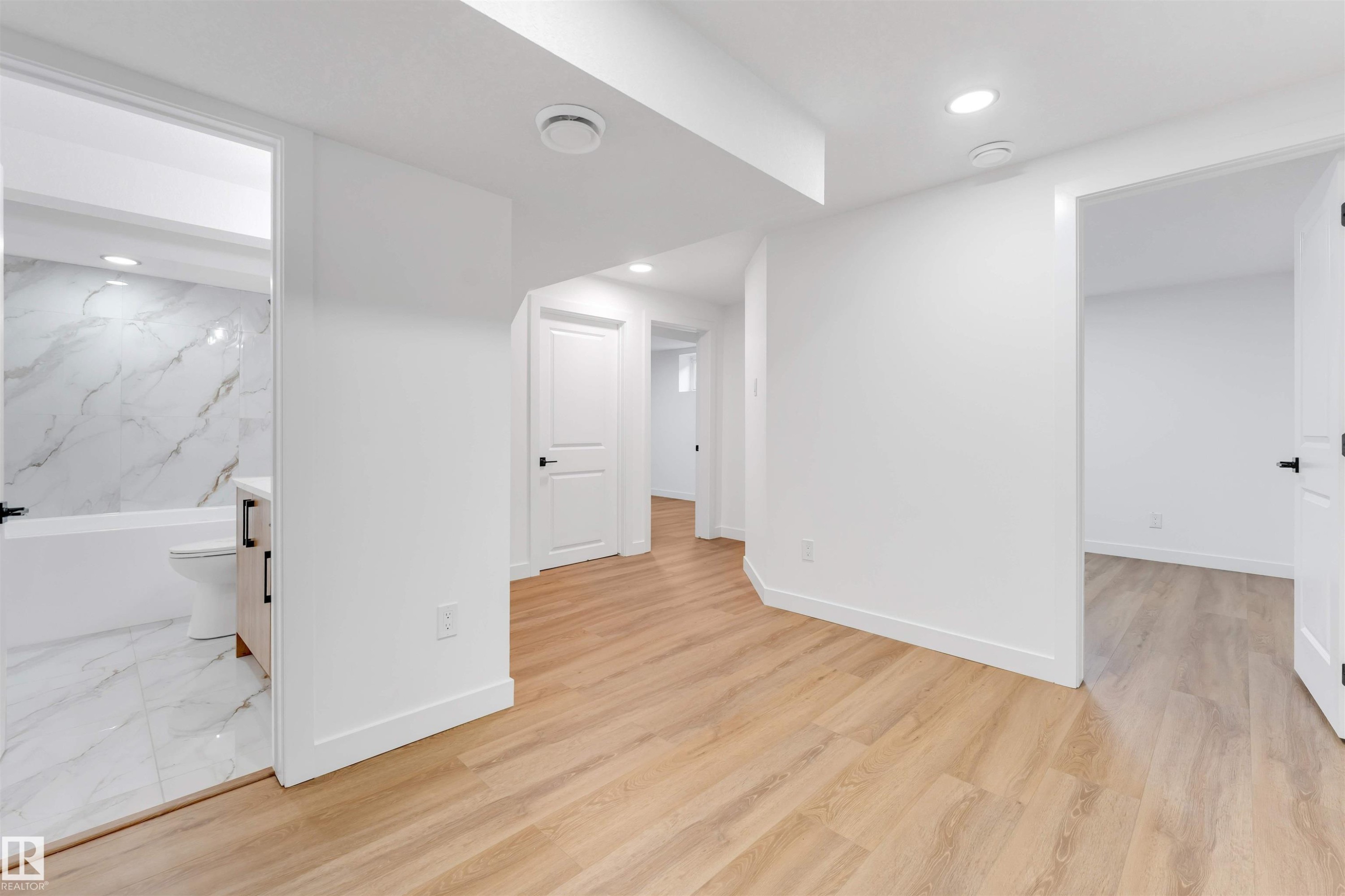Light wood-finish flooring throughout, complemented by white walls and trim - 5512 150 Avenue, Edmonton, AB