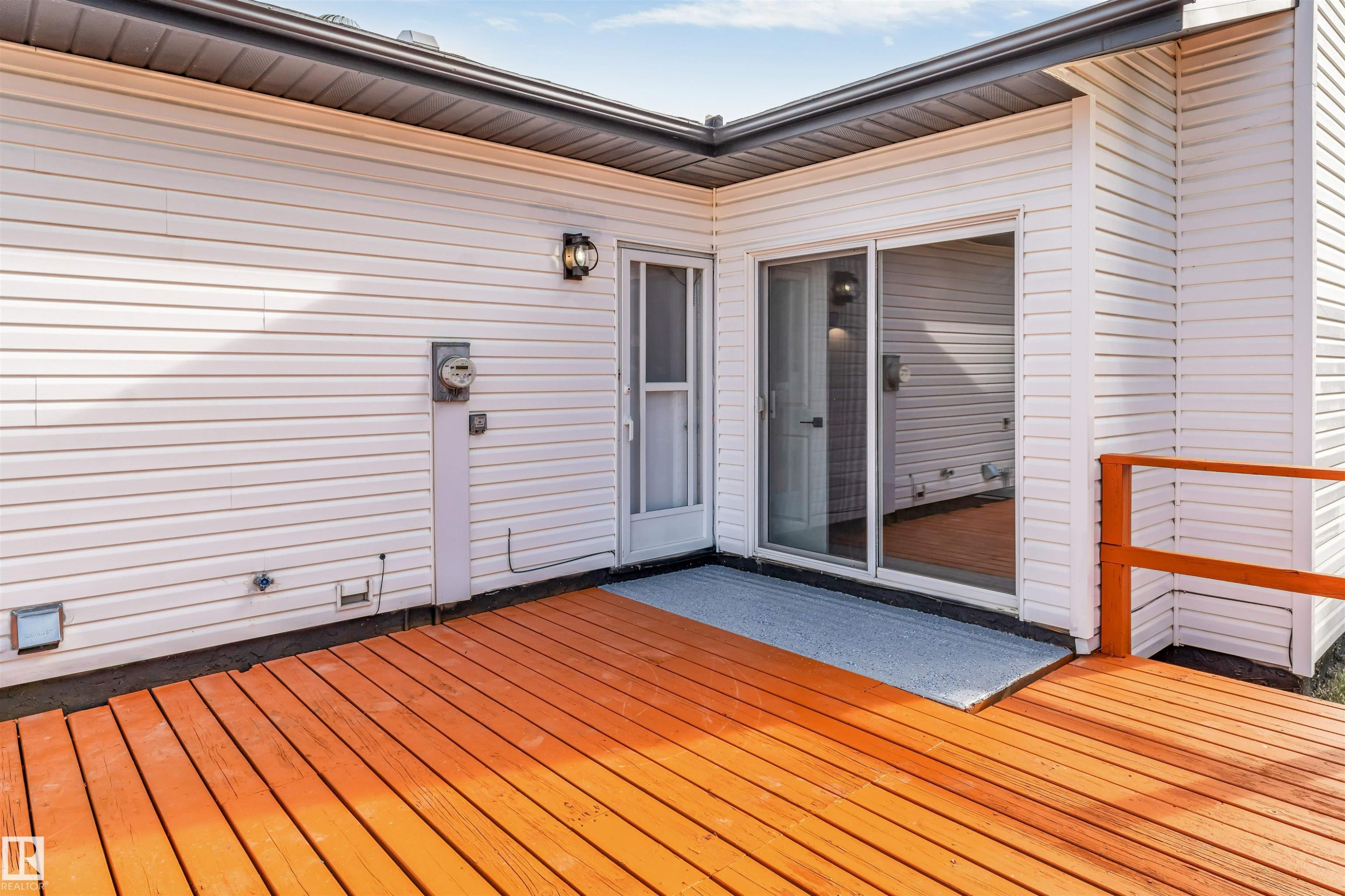 Expansive outdoor deck featuring wood flooring and a bright orange railing - 5512 150 Avenue, Edmonton, AB