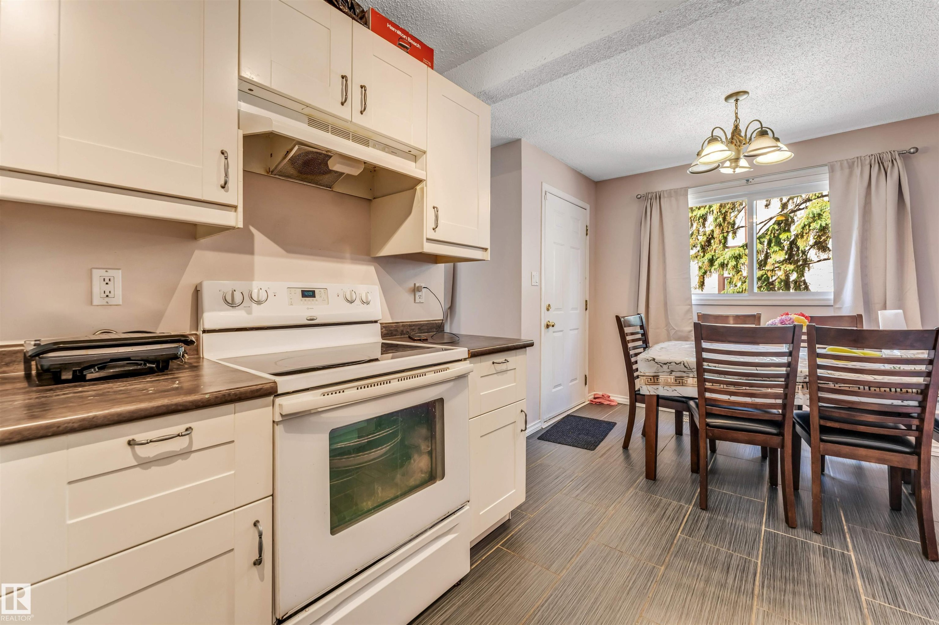 Kitchen featuring white cabinetry, dark countertops, a white electric range, and tile flooring - 24 1651 46 Street, Edmonton, AB