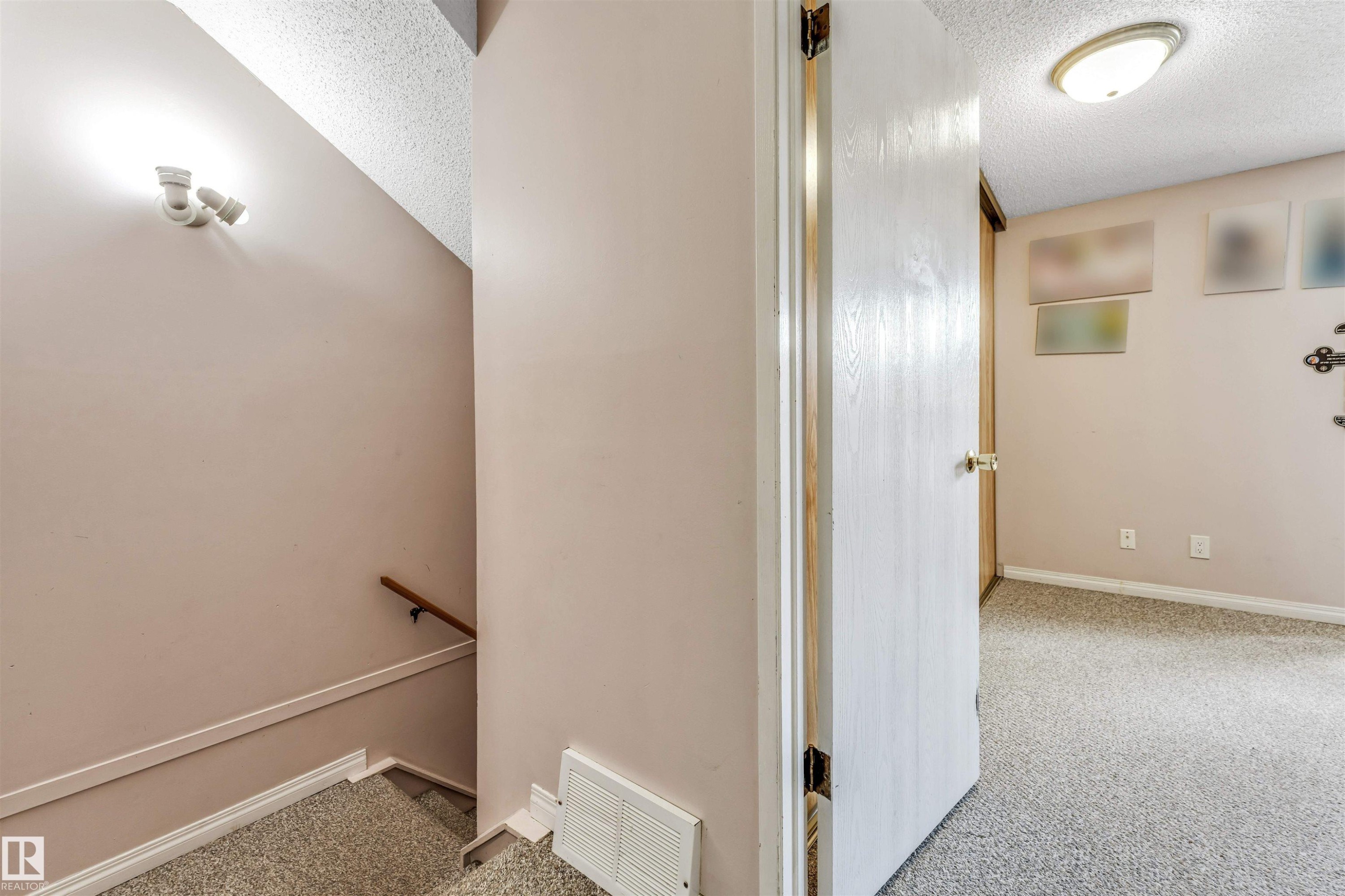 Interior space featuring neutral wall paint, a textured ceiling, and a doorway leading to a carpeted room - 24 1651 46 Street, Edmonton, AB