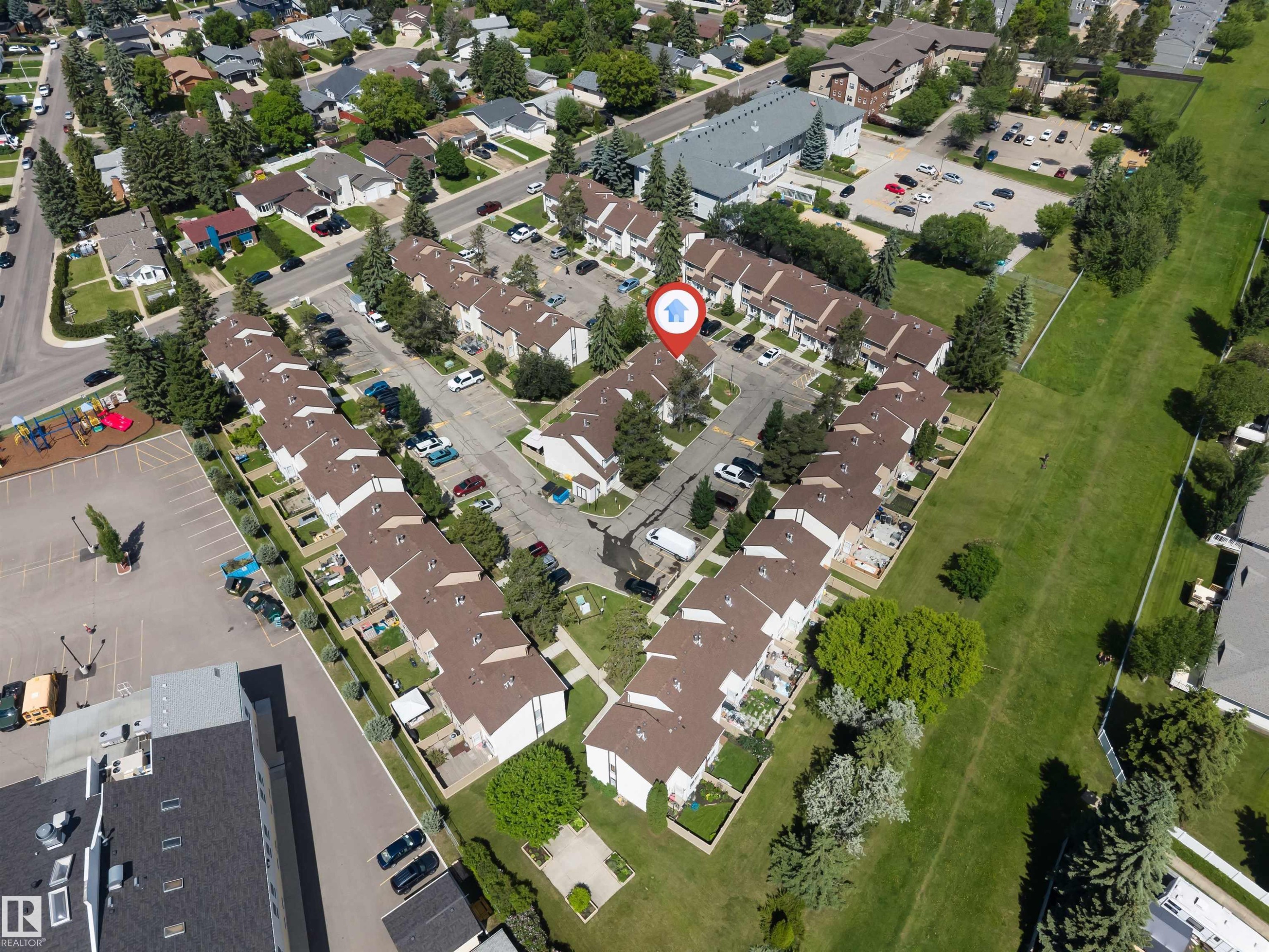 Aerial view of a residential complex with brown-roofed townhomes, featuring multiple private patios, individual parking spaces, mature landscaping, and a central courtyard area - 24 1651 46 Street, Edmonton, AB