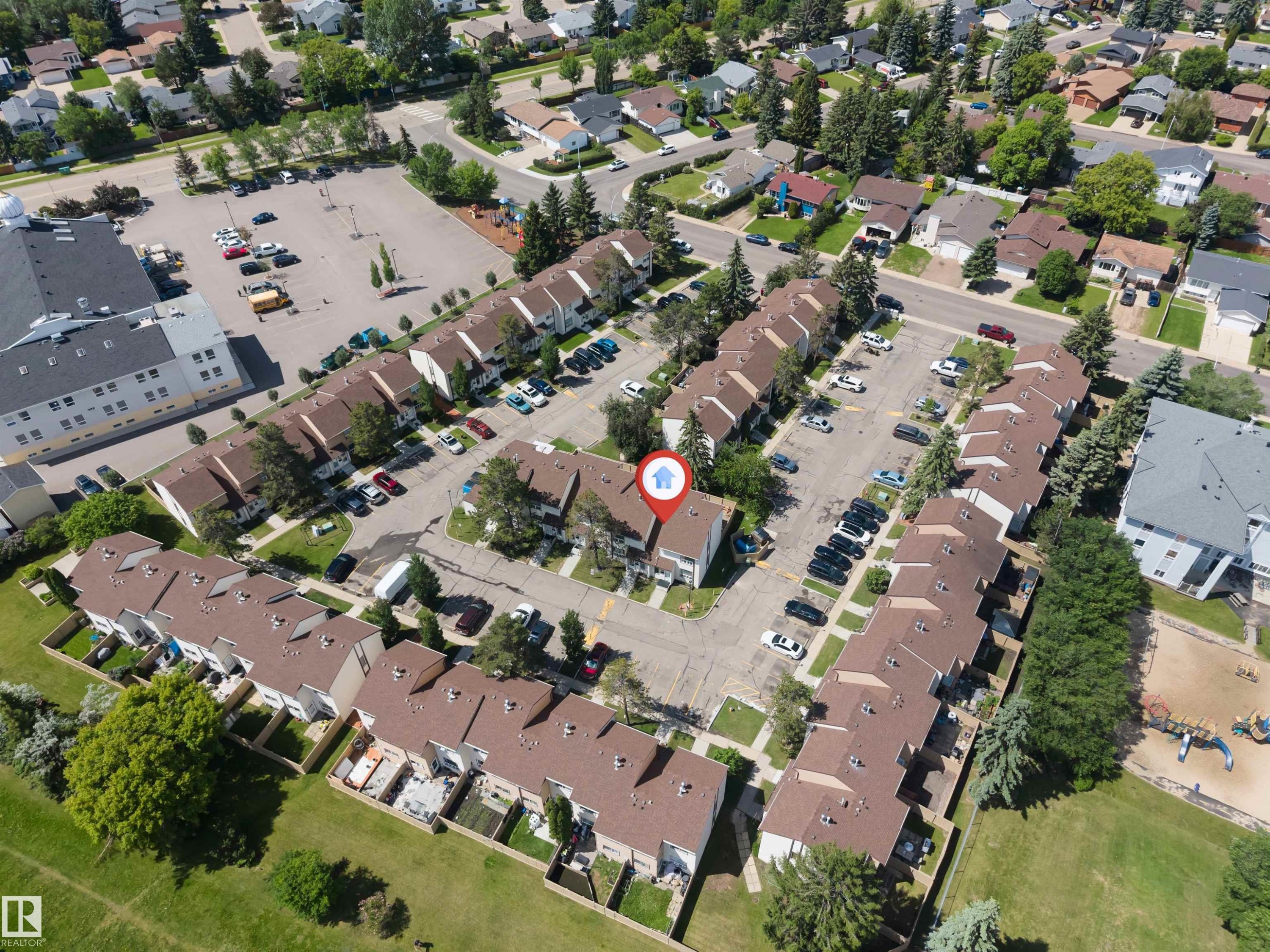 Townhome community featuring brown shingle roofs, individual patios, paved parking areas, and surrounding green spaces - 24 1651 46 Street, Edmonton, AB
