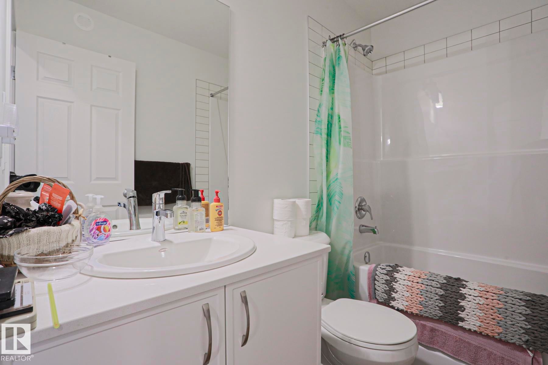 Bathroom featuring a white vanity with an integrated sink, chrome faucet, and mirrored wall - 33 Eton Link, Spruce Grove, AB