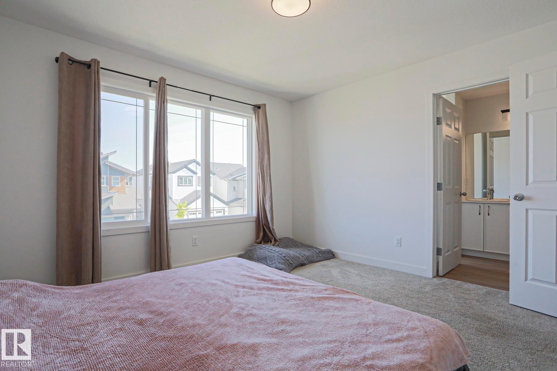 Bedroom featuring a large window, neutral carpeting, and a built-in overhead light fixture - 33 Eton Link, Spruce Grove, AB