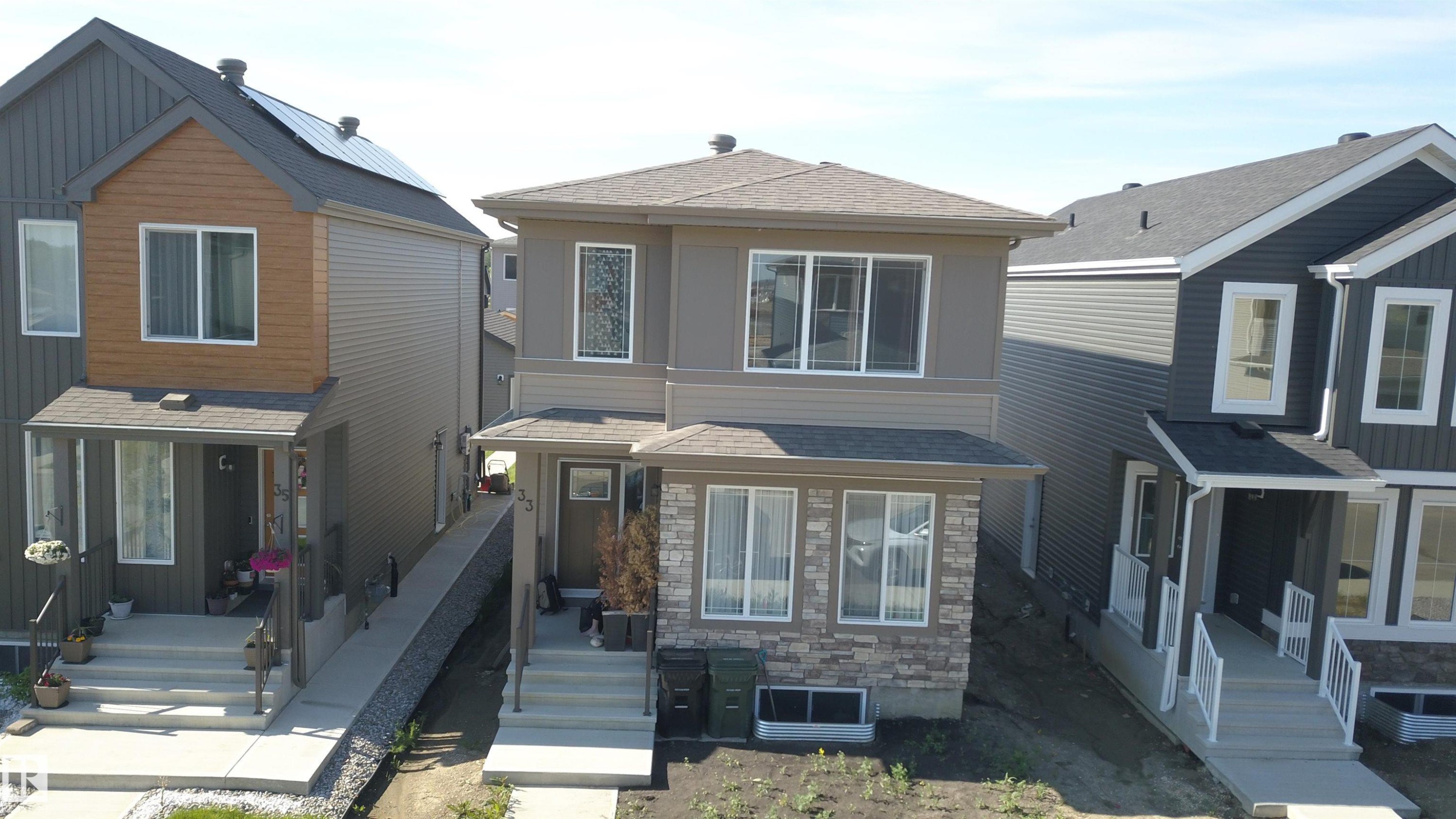 Two-story residence featuring a stone and siding facade, a covered front entry, and multiple windows - 33 Eton Link, Spruce Grove, AB