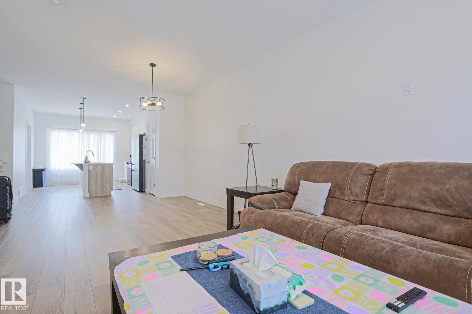 Open-concept living space featuring light wood-finish flooring and neutral wall tones - 33 Eton Link, Spruce Grove, AB