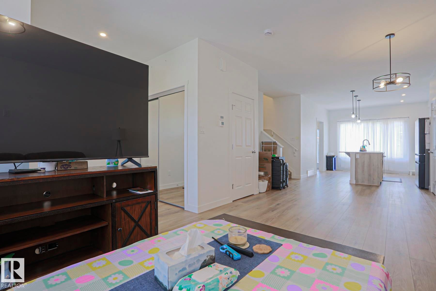 Open-concept living area featuring light wood-finish flooring, recessed lighting, and a contemporary kitchen island with pendant lighting - 33 Eton Link, Spruce Grove, AB