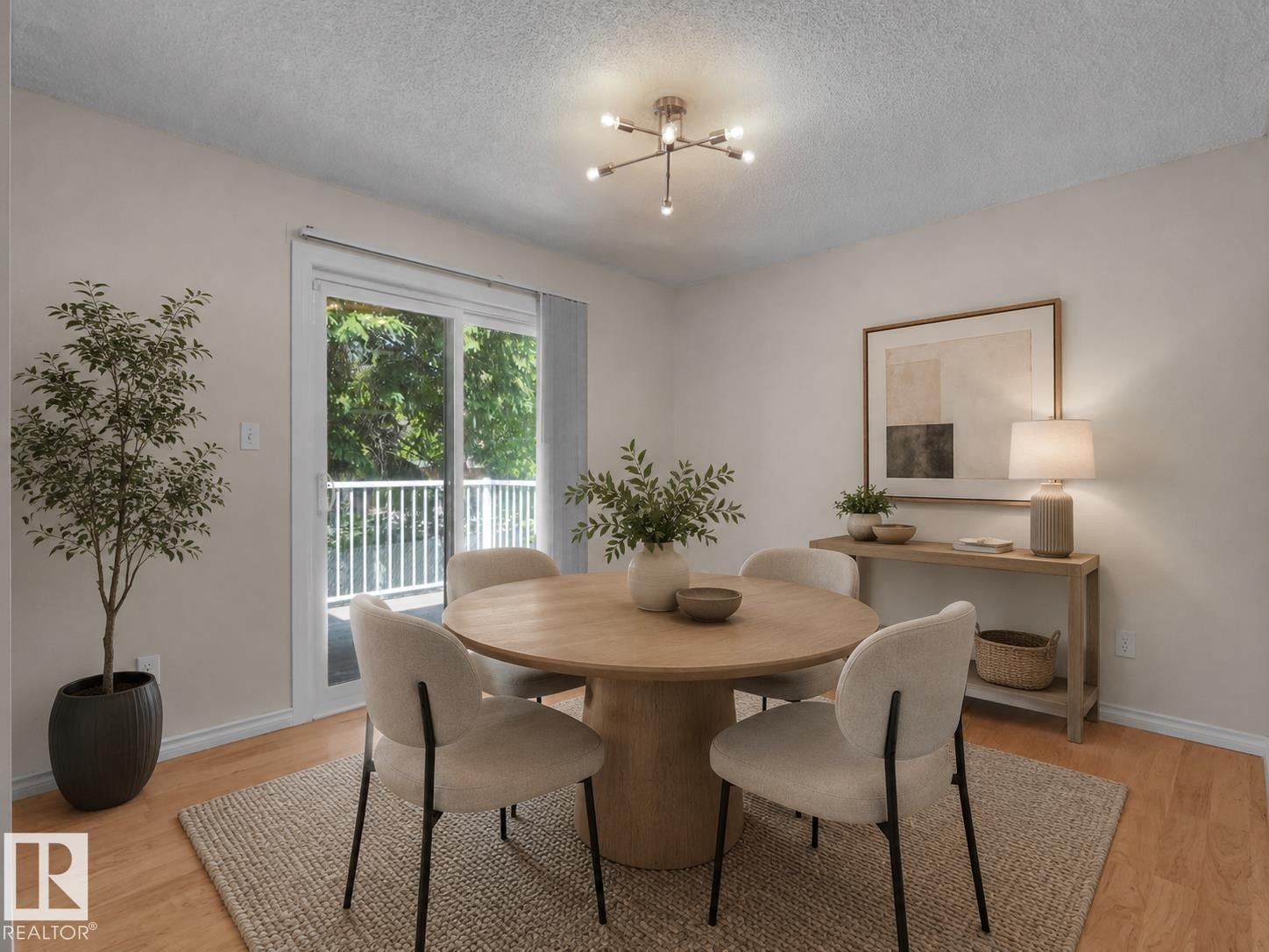 Dining area featuring wood-finish flooring, a modern ceiling light fixture, and direct access to an outdoor balcony with white railings - 1855 Mill Woods Rd E Nw, Edmonton, AB