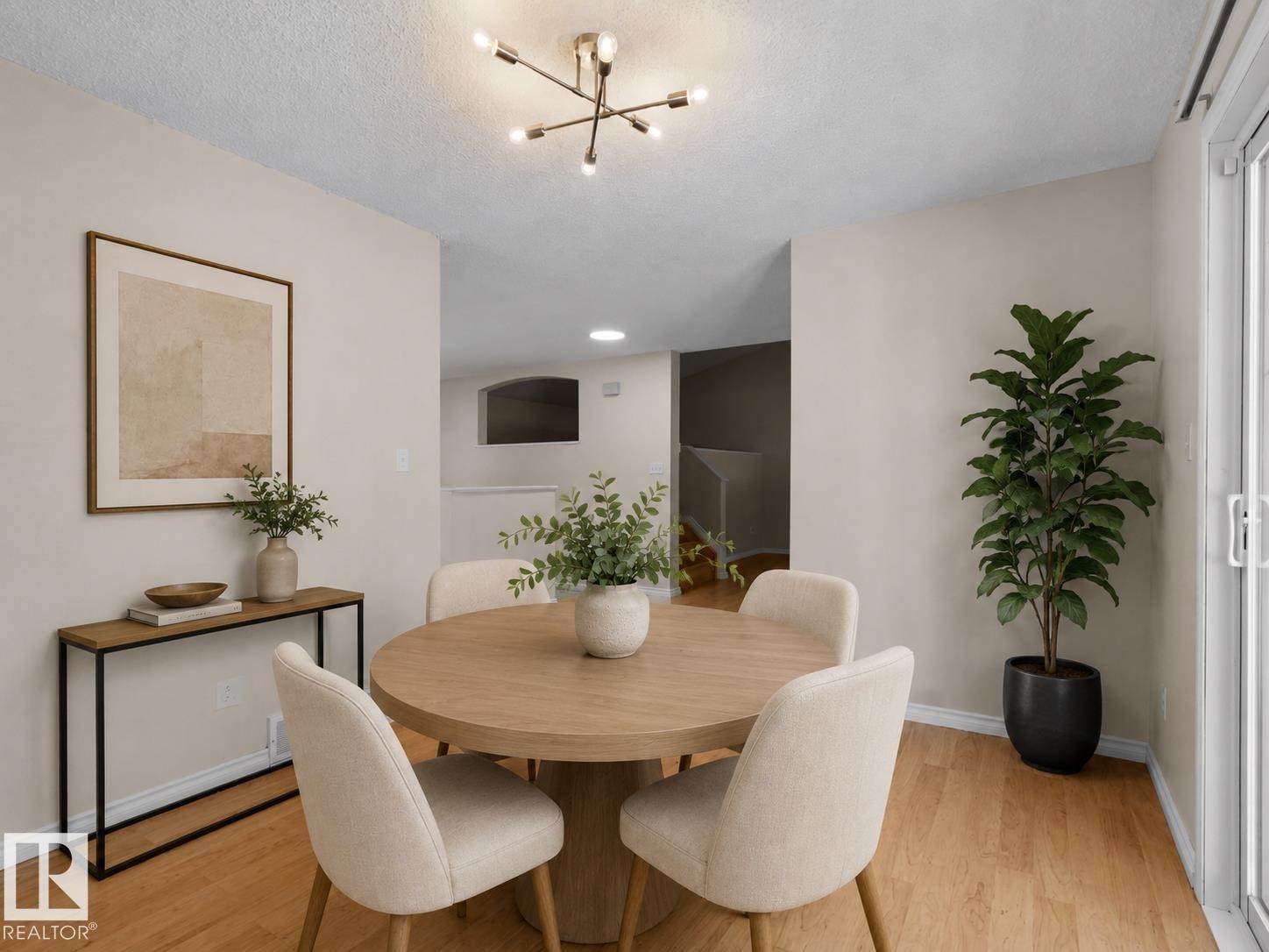 Open-concept dining area featuring wood-finish flooring, a contemporary ceiling light fixture, neutral wall finishes, and a sliding glass door - 1855 Mill Woods Rd E Nw, Edmonton, AB